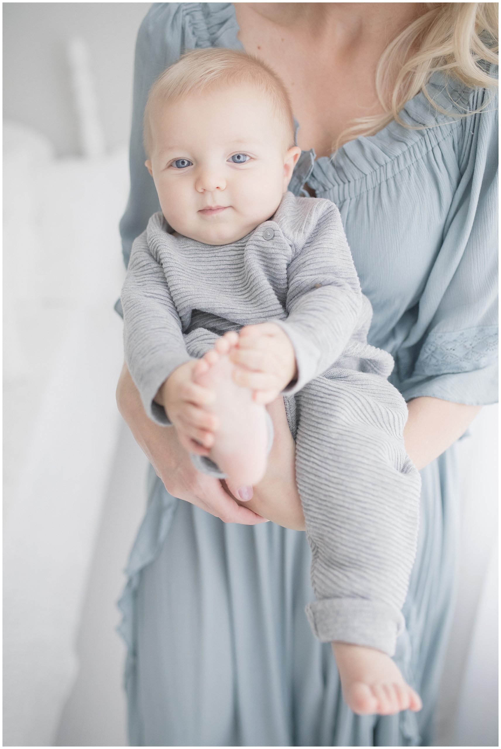 Blue eyed boy held by his momma. Photo by Little Sunshine Photography.