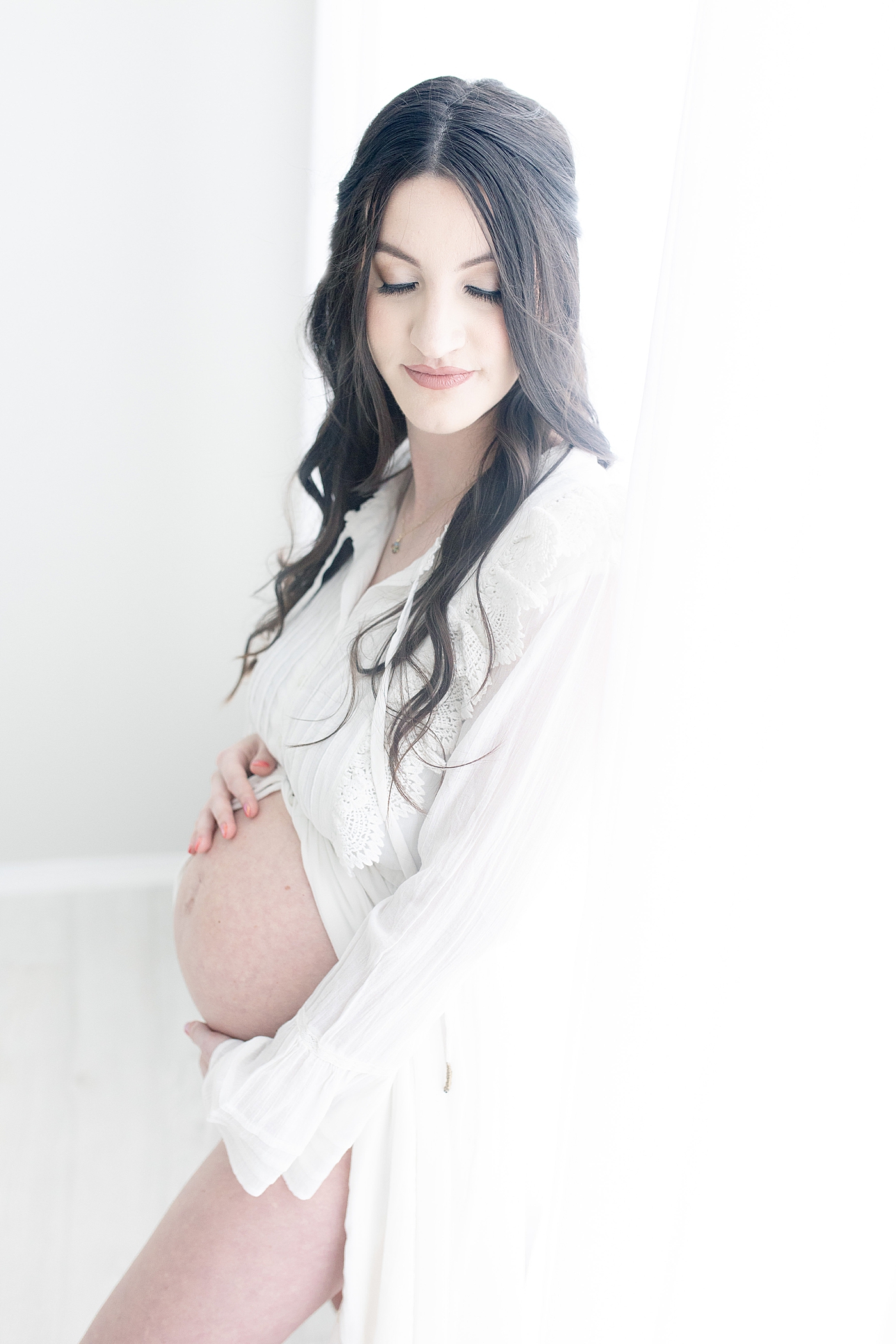 Mom embracing her bare belly during maternity photos. Photo by Little Sunshine Photography.