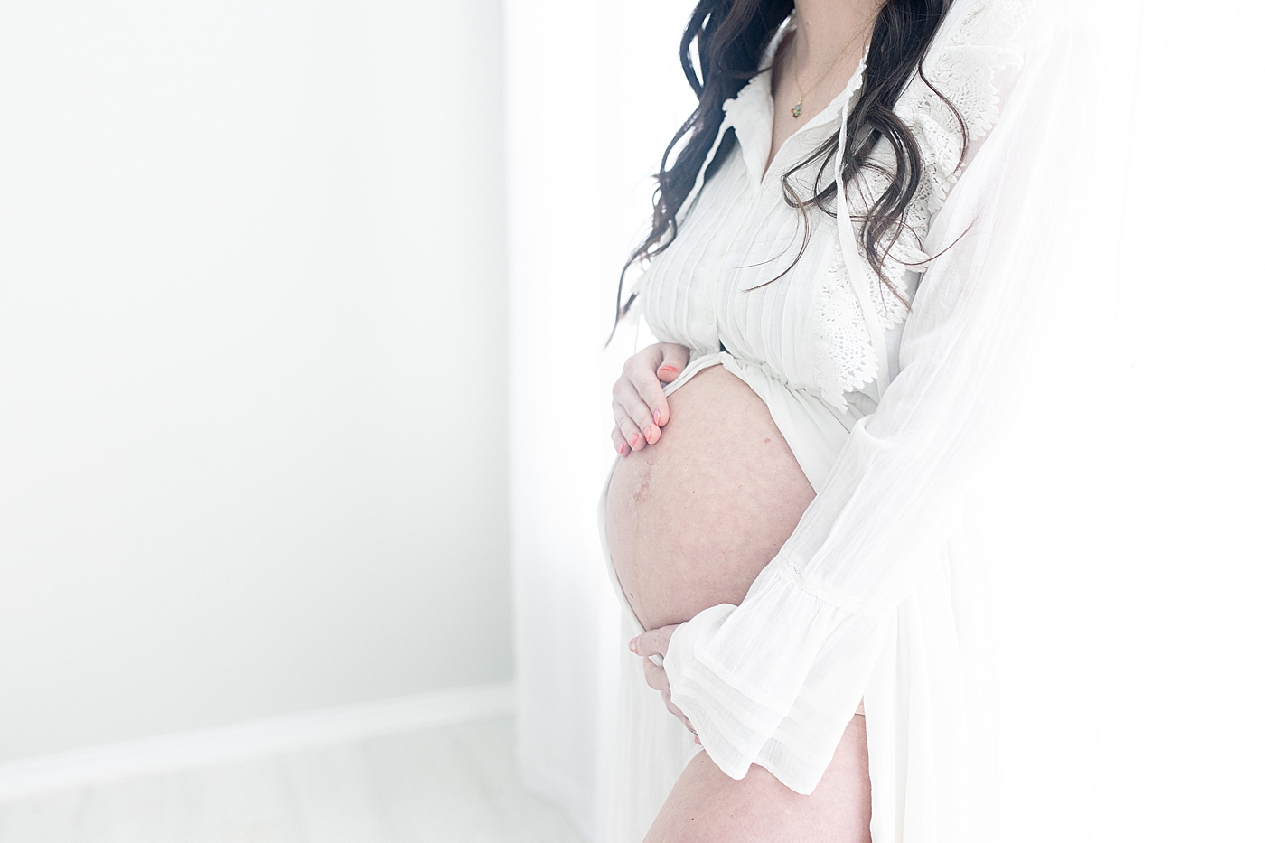 Maternity portraits of Mom embracing her pregnant belly. Photo by Little Sunshine Photography.