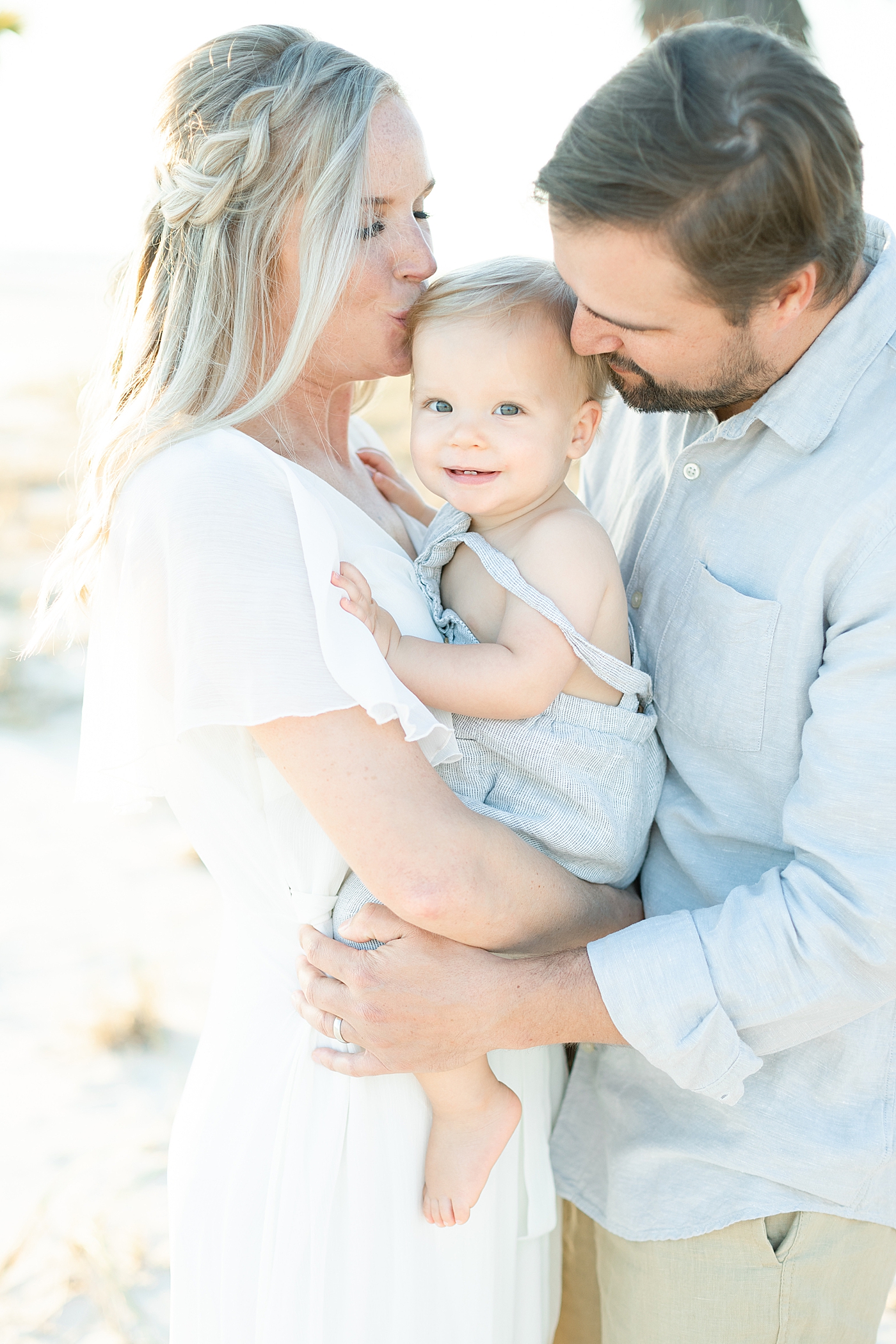 Mom and Dad kissing their son. Photo by Little Sunshine Photography.