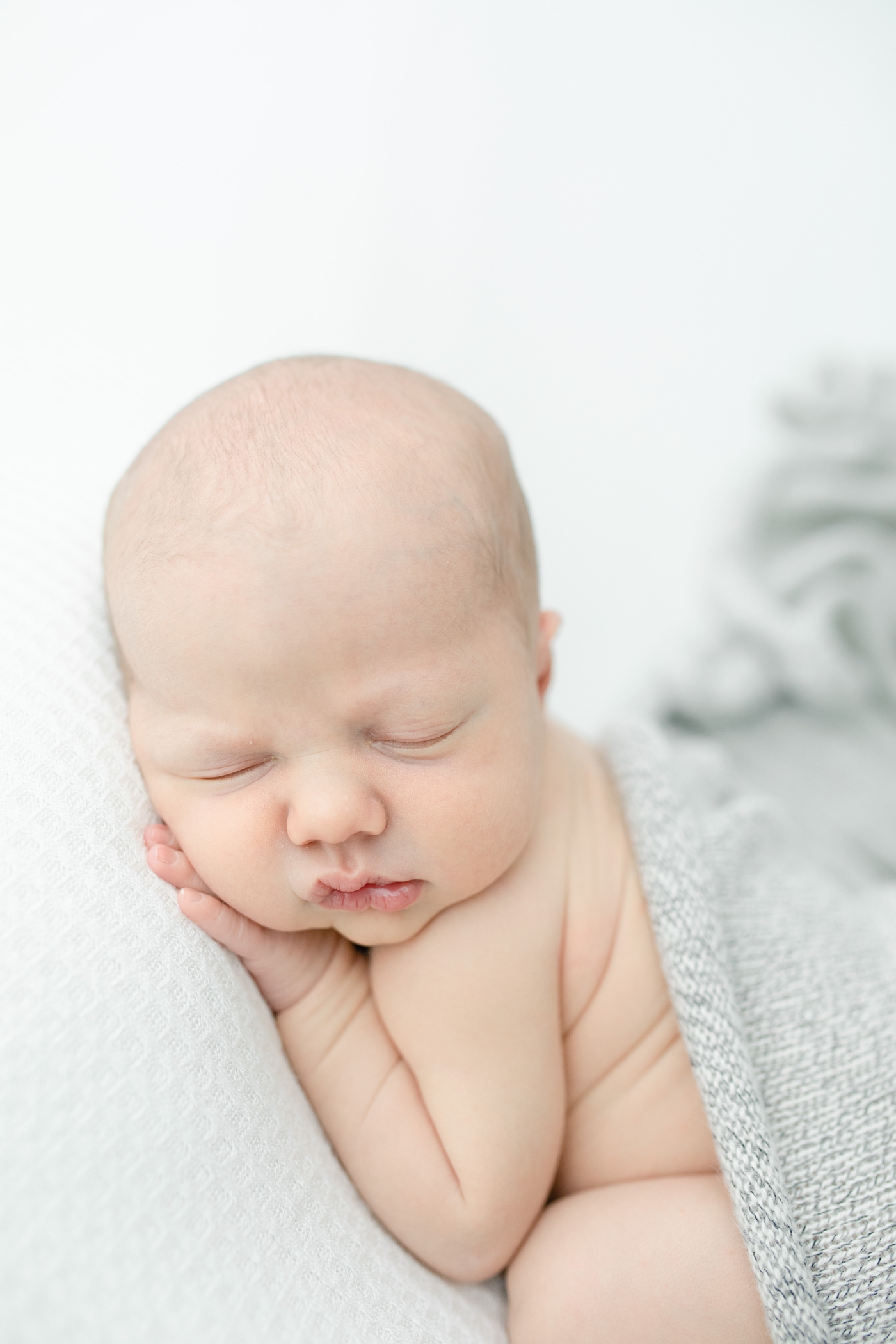 Baby boy during posed newborn session with grey knit wrap. Photo by Little Sunshine Photography.
