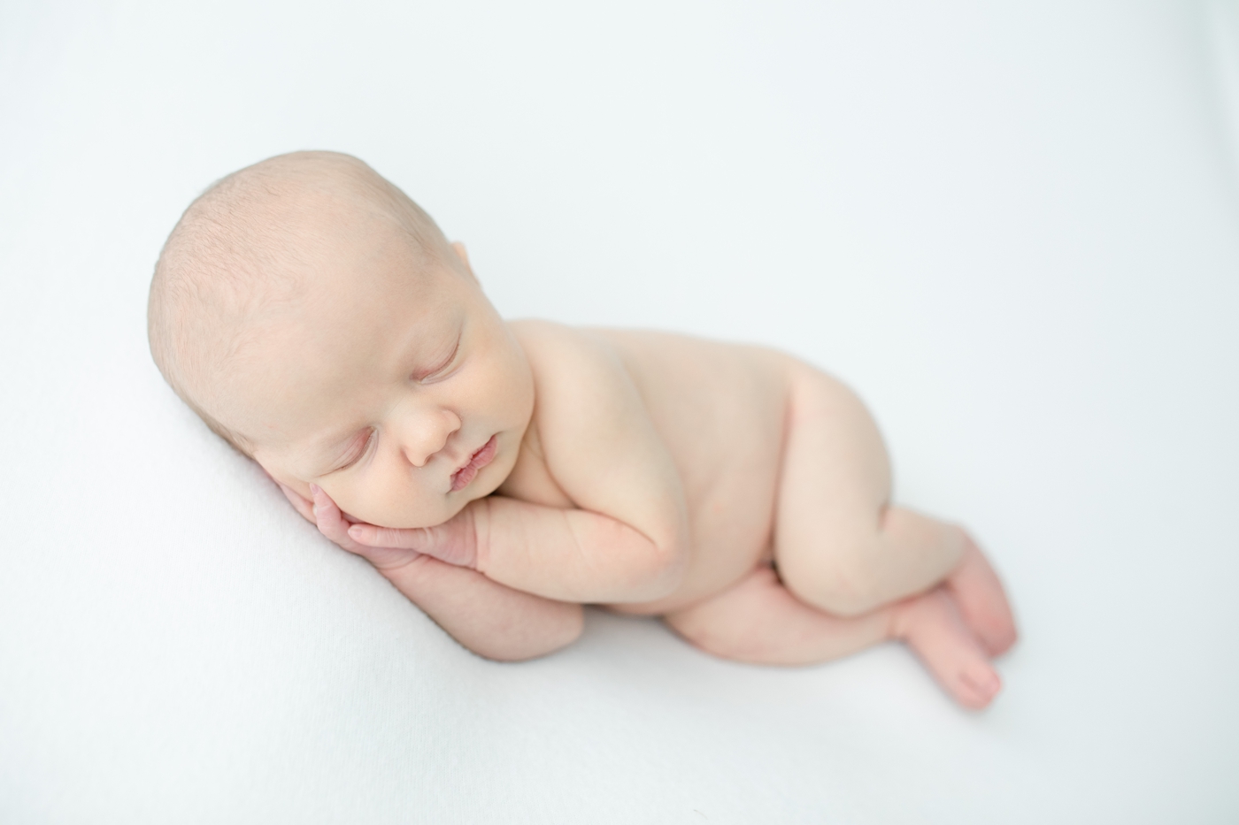 Simple and classic newborn image with baby boy's hands folded under chin. Photo by Little Sunshine Photography.