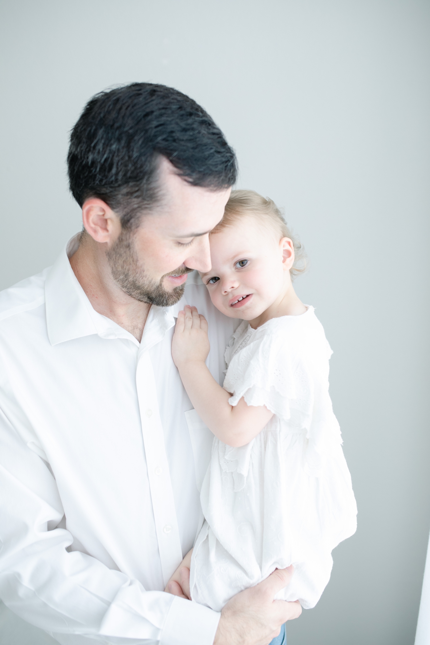 Dad holding toddler during newborn session in studio. Photo by Little Sunshine Photography.