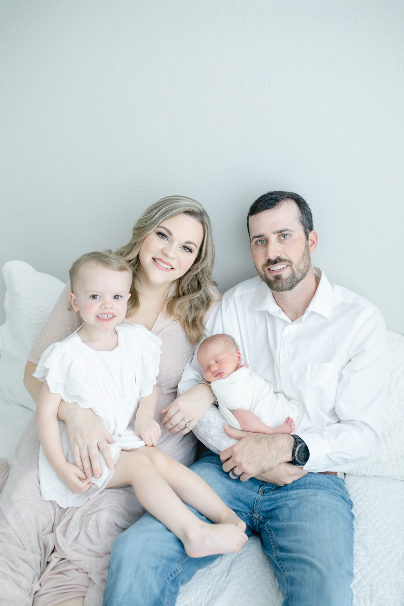 Family smiling at camera during newborn session in Gulf Shores, MS. Photo by Little Sunshine Photography.