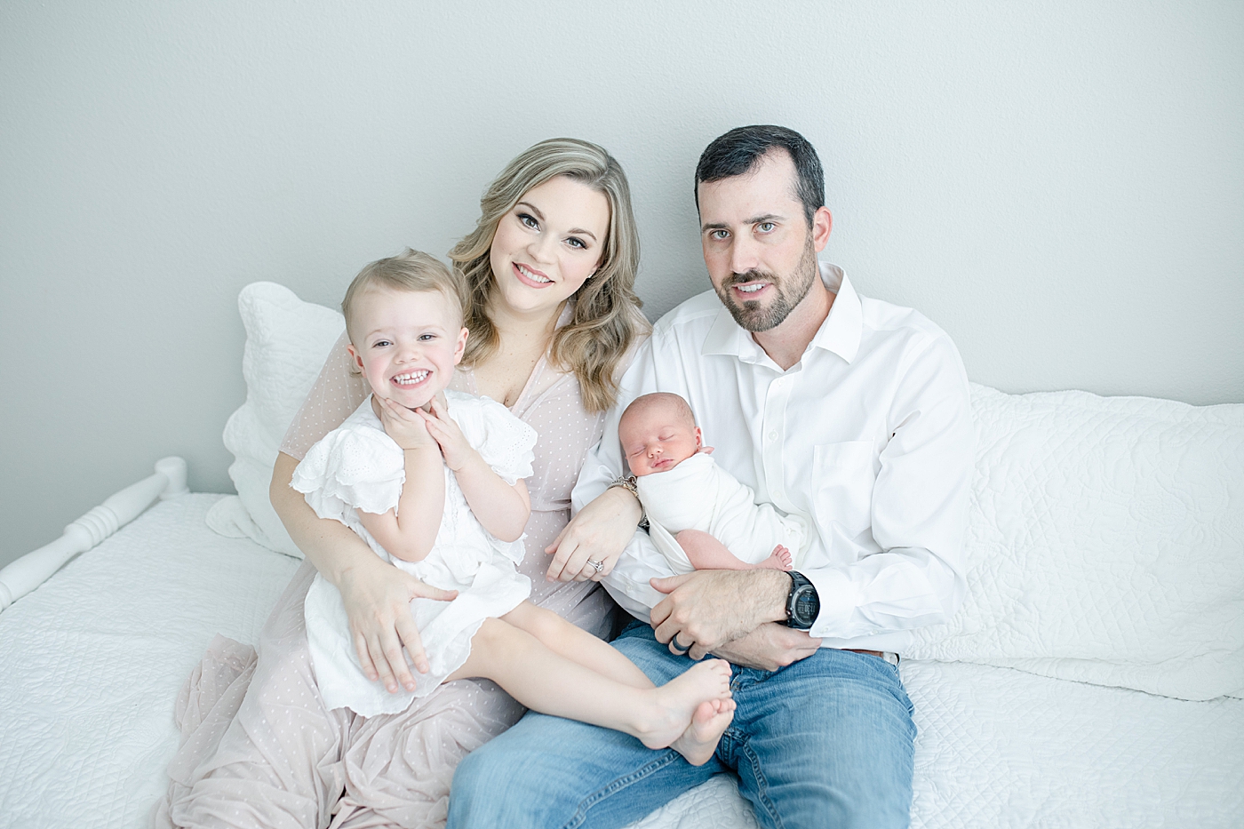 Family and sibling photos on bed during newborn session. Sweet image by Little Sunshine Photography.