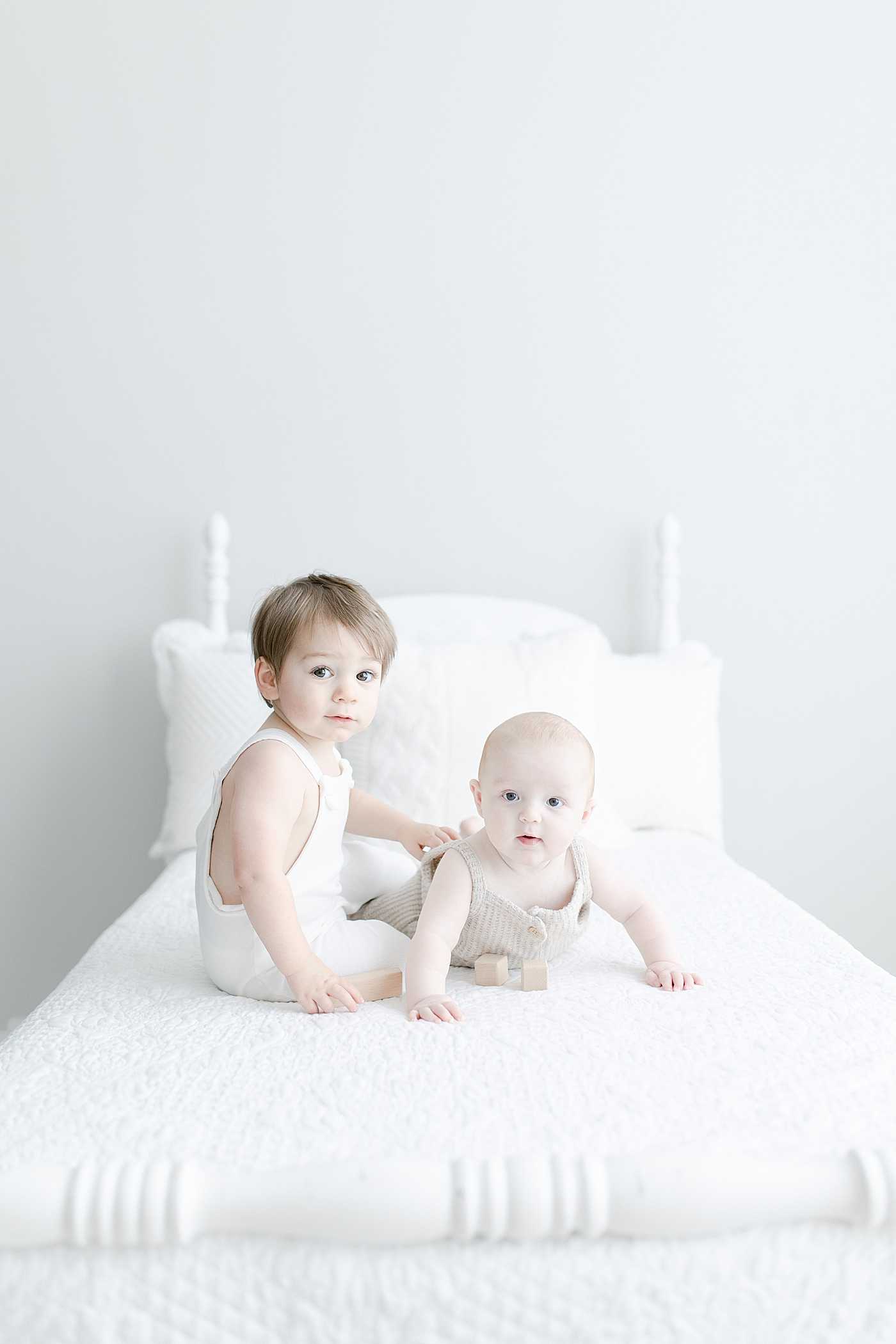Two brothers, less than a year apart, sitting on bed together. Photo by Little Sunshine Photography