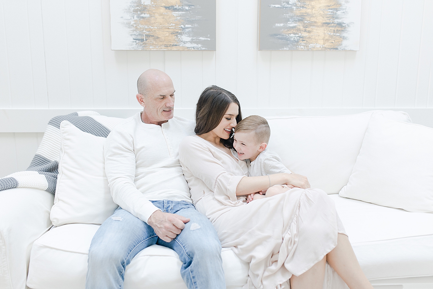 Mom, Dad and son on couch during family photoshoot in their home. Photo by Little Sunshine Photography