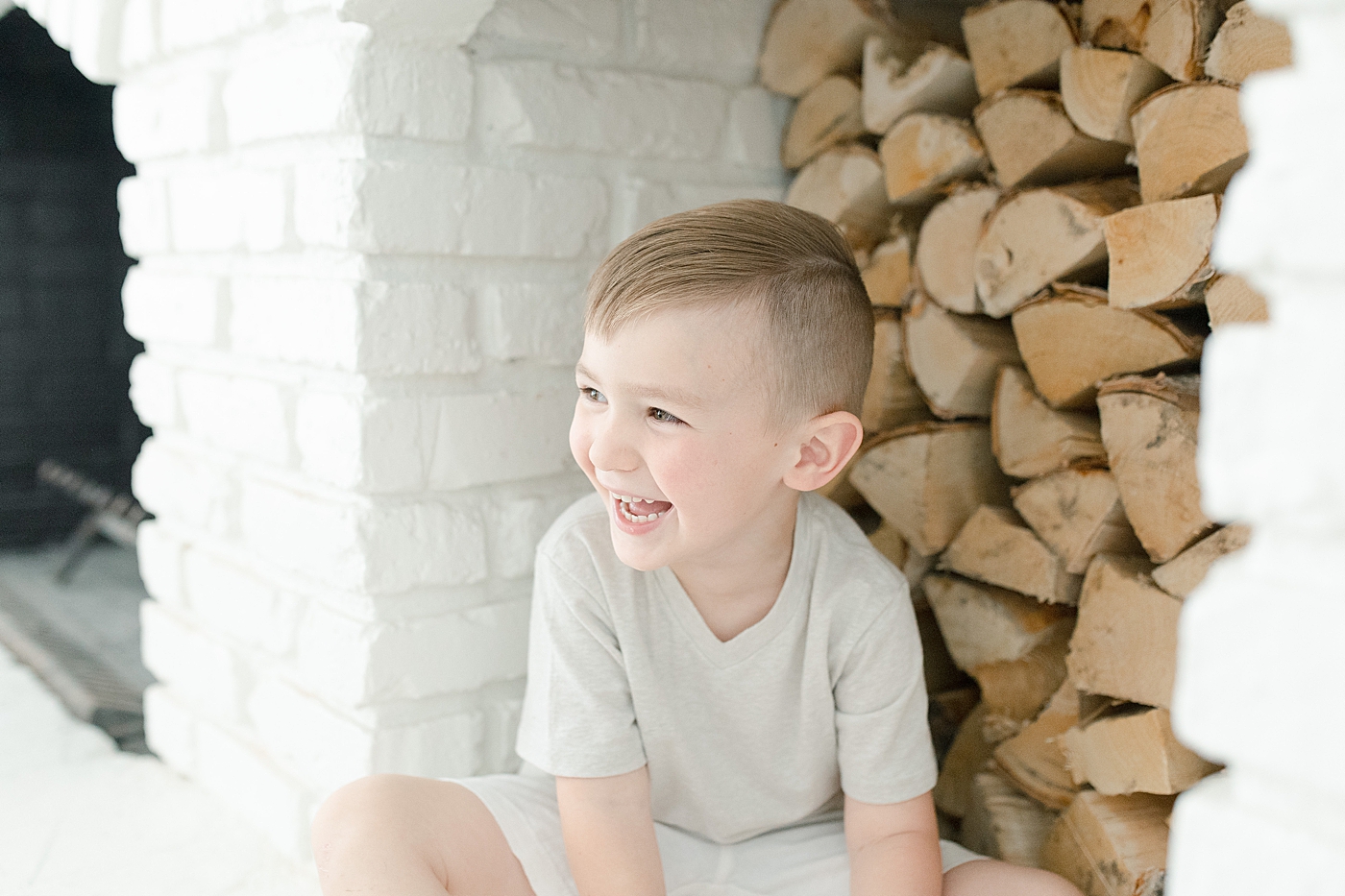 Toddler boy playing on fireplace during in-home family photoshoot. Photo by Little Sunshine Photography