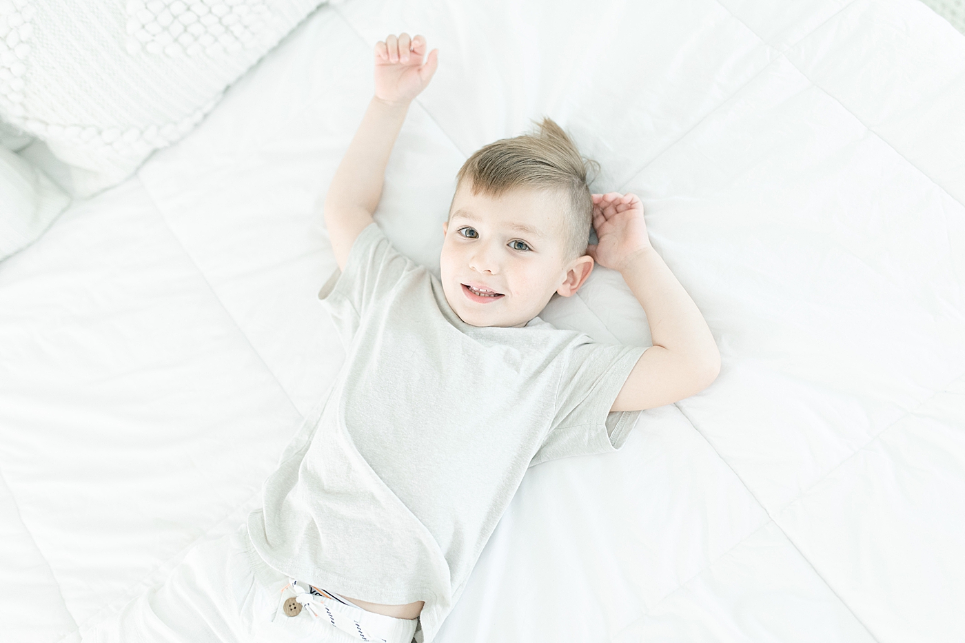 Toddler boy laying on bed. Photo by Little Sunshine Photography