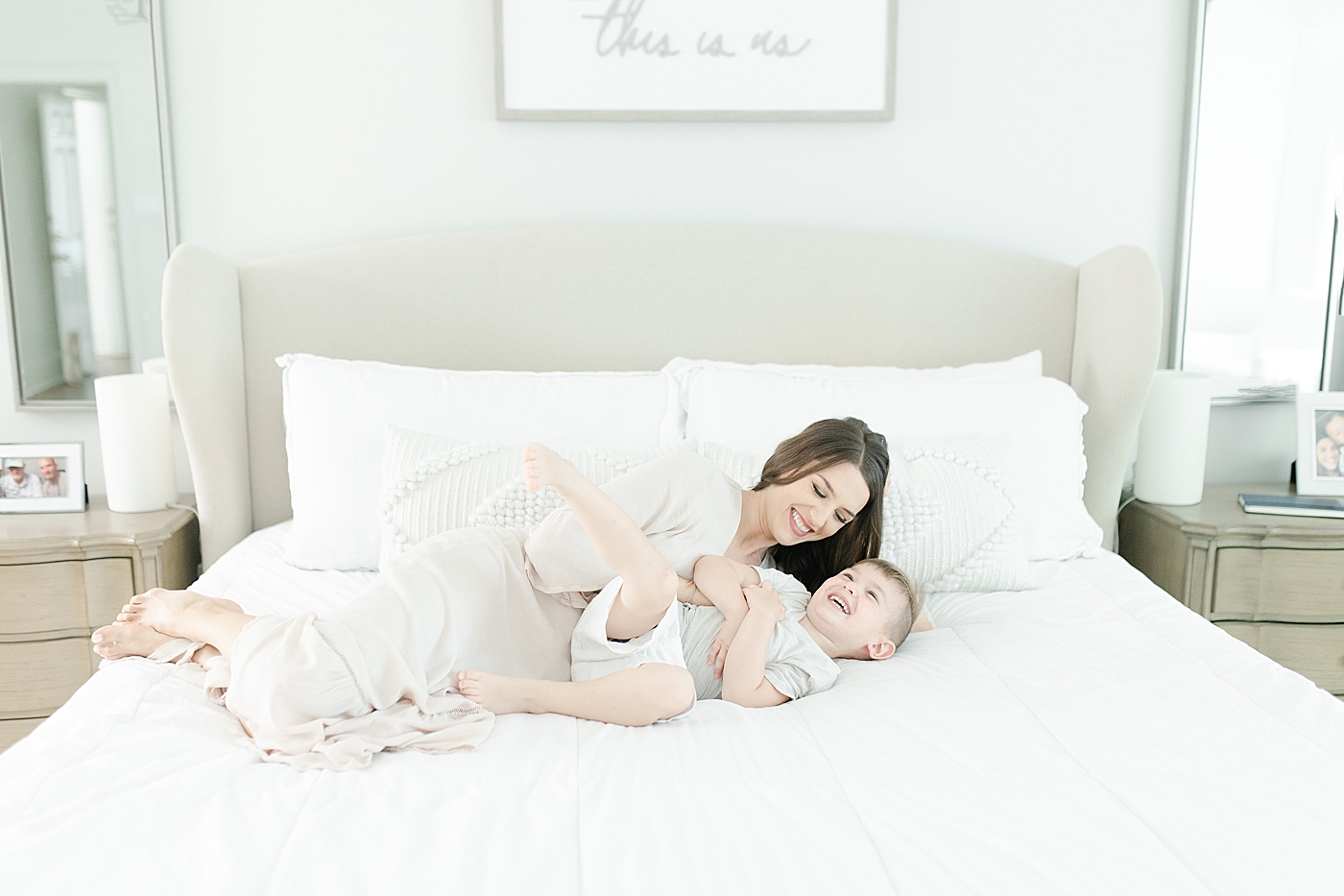 Mom tickling son on bed during family photoshoot. Photo by Little Sunshine Photography