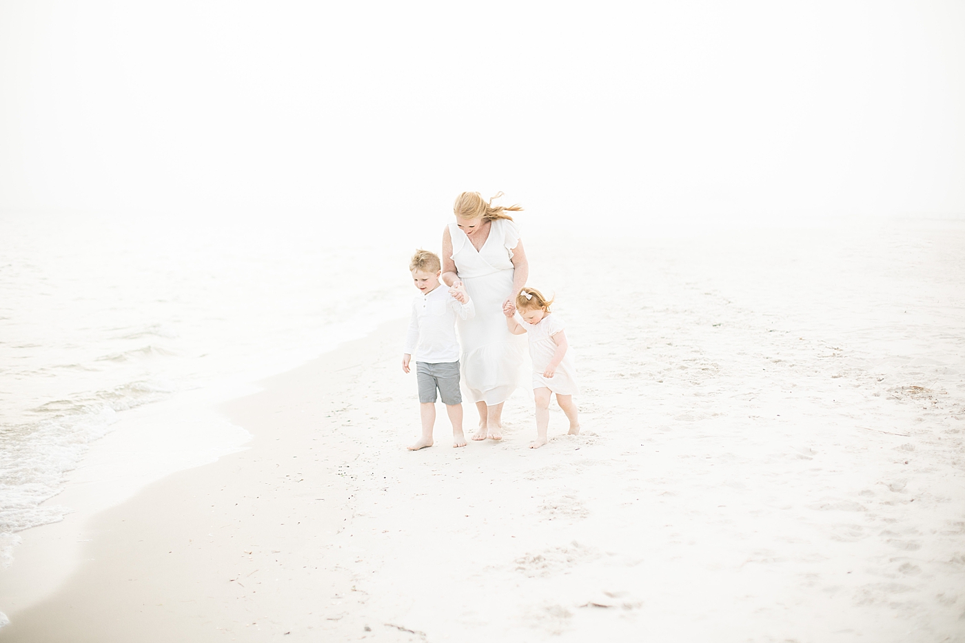 Mom walking with her two kids along the water on the beach. Photo by Little Sunshine Photography.