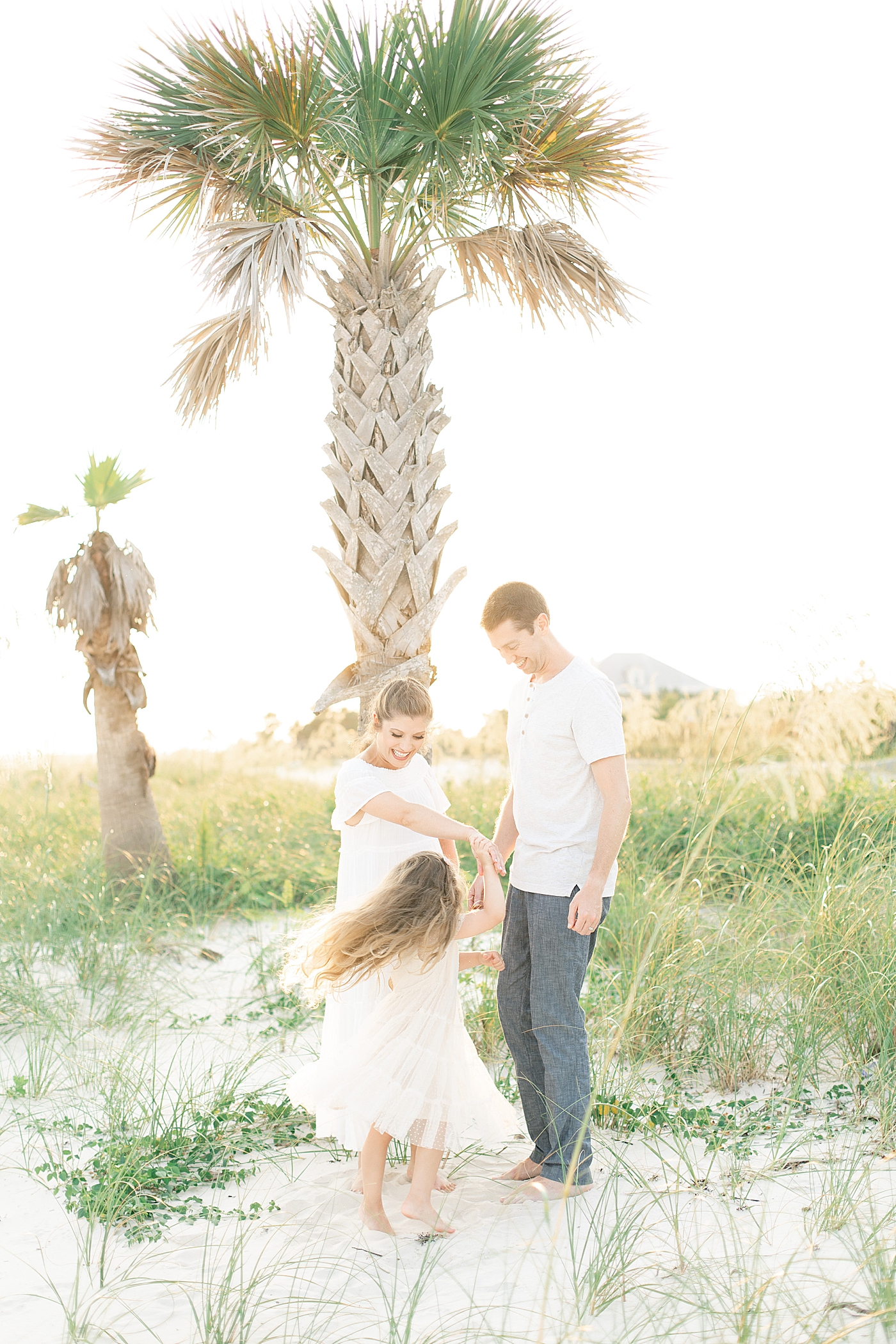 Family dancing on the beach at Ocean Springs during maternity session. Photo by Little Sunshine Photography.