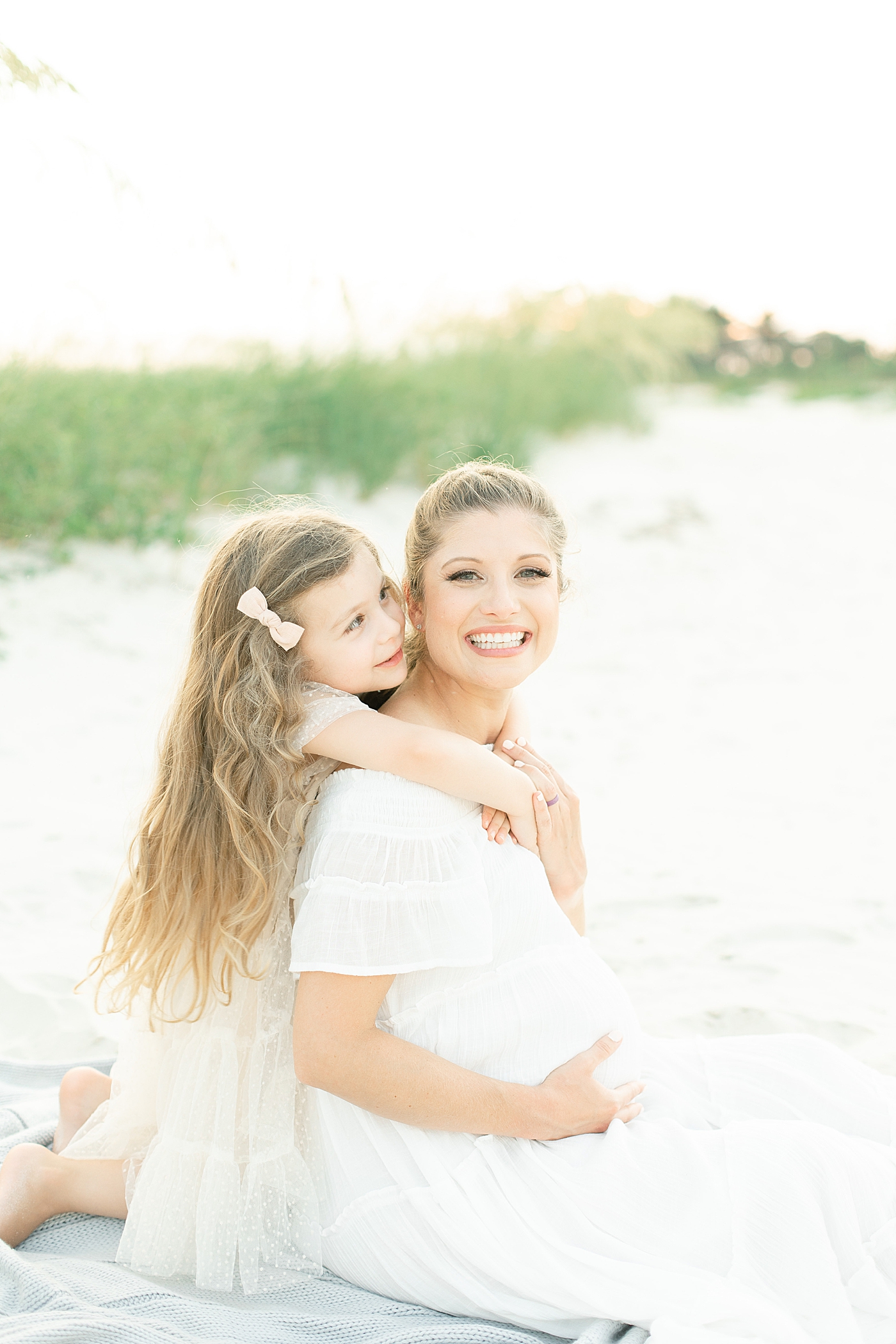Mom and daughter sitting in the sand at ocean springs. Photo by Little Sunshine Photography.