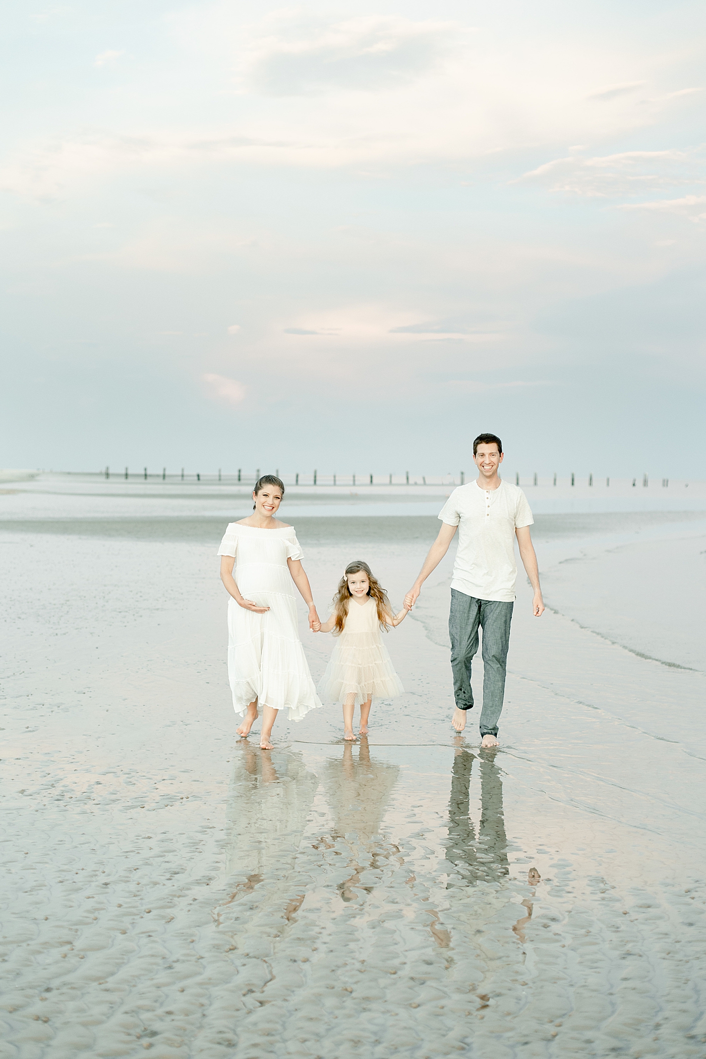 Family walking along the water on the beach. Photo by Little Sunshine Photography.