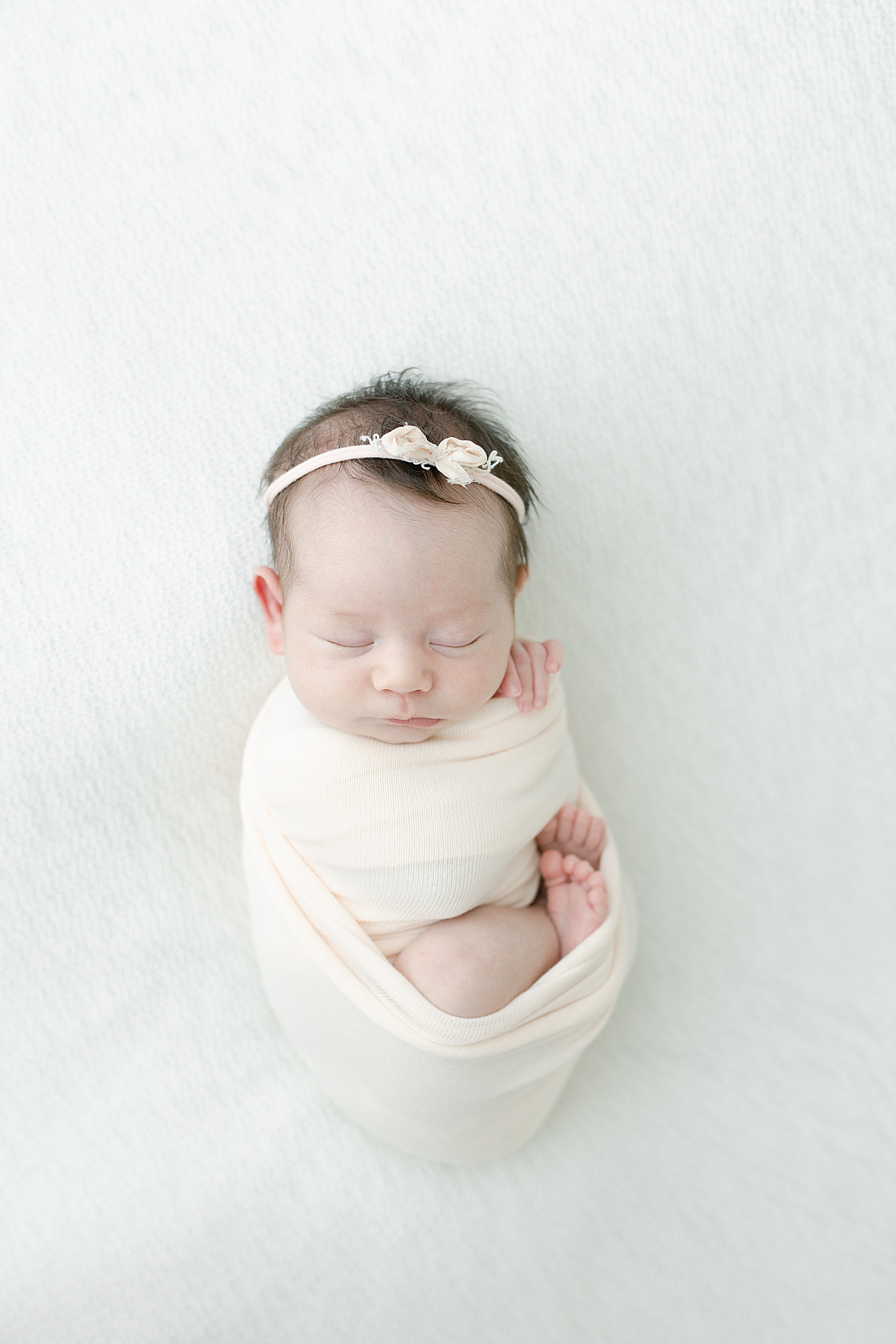 Baby girl swaddled with feet and hands peeking out during newborn session. Photo by Little Sunshine Photography