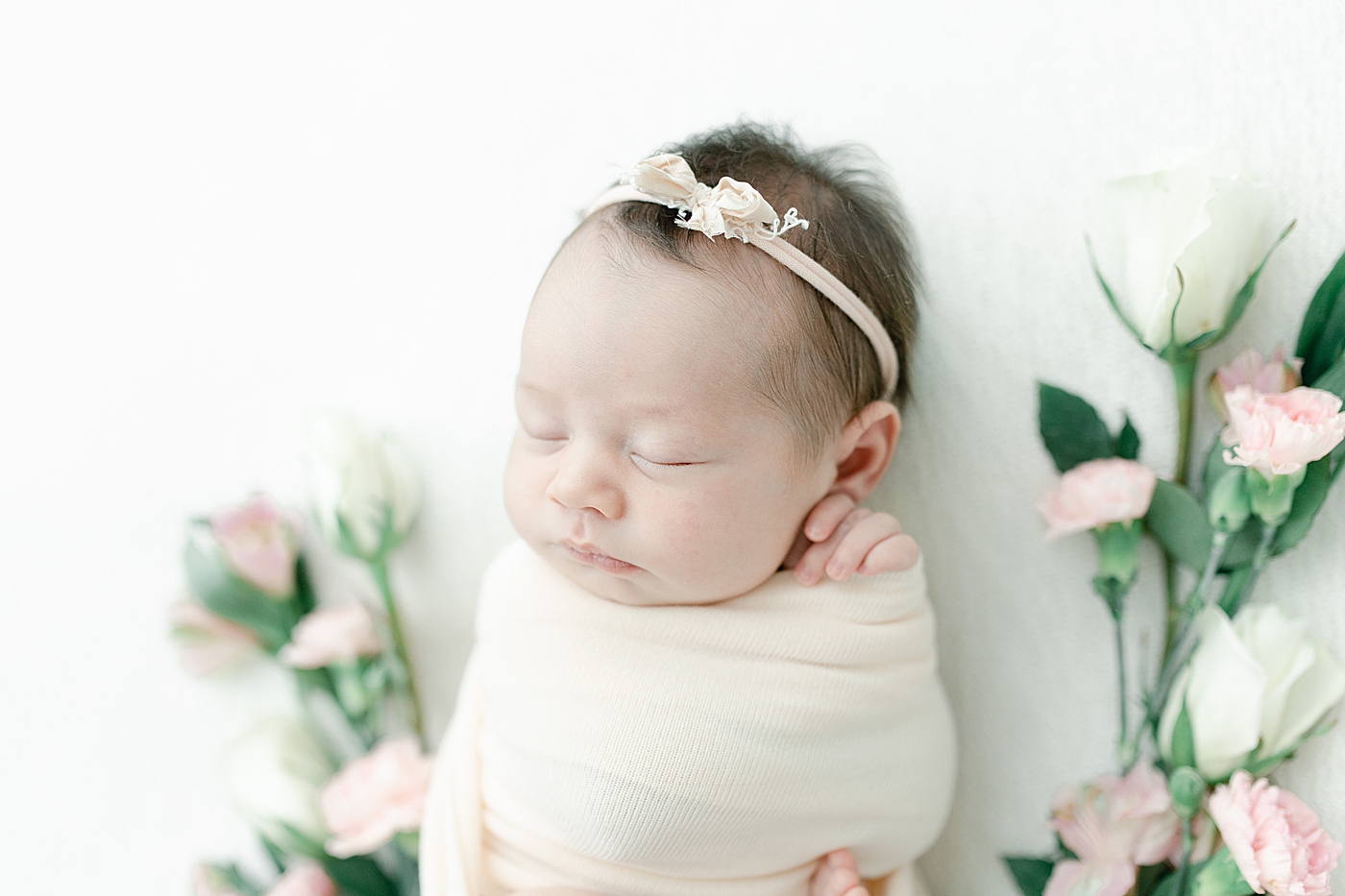 Newborn photo of baby girl surrounded by flowers. Photo by Little Sunshine Photography