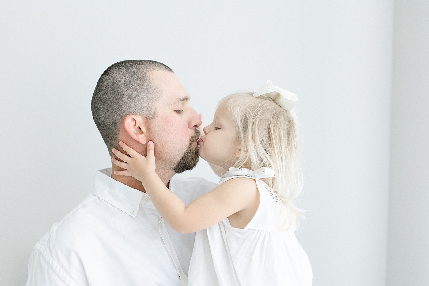 Toddler giving daddy a kiss during newborn session in Pascagoula. Photo by Little Sunshine Photography.