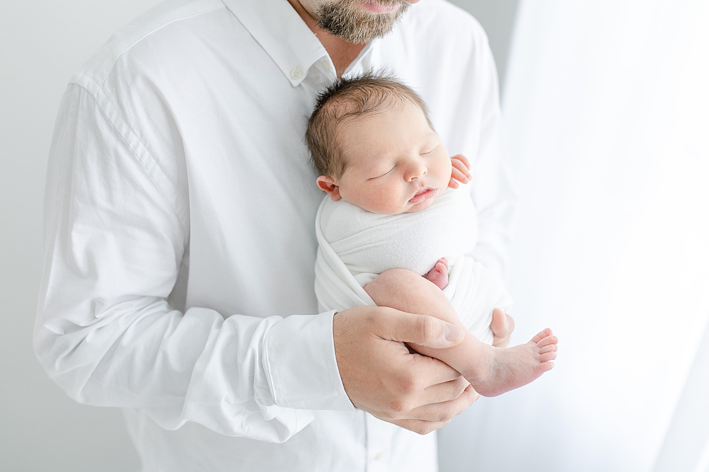 Dad holding newborn son. Photo by Little Sunshine Photography.