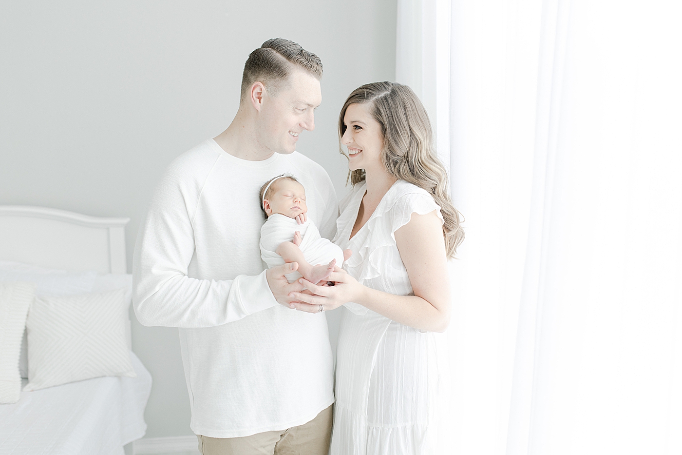 Mom and dad holding newborn baby girl | Photo by Little Sunshine Photography