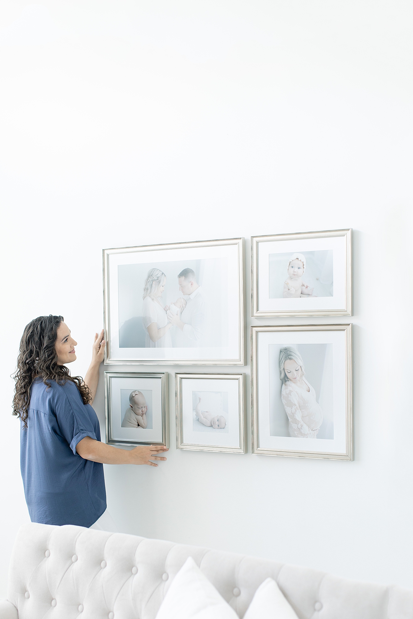 Photographer hanging a custom gallery wall in a client's home | Photo by Little Sunshine Photography