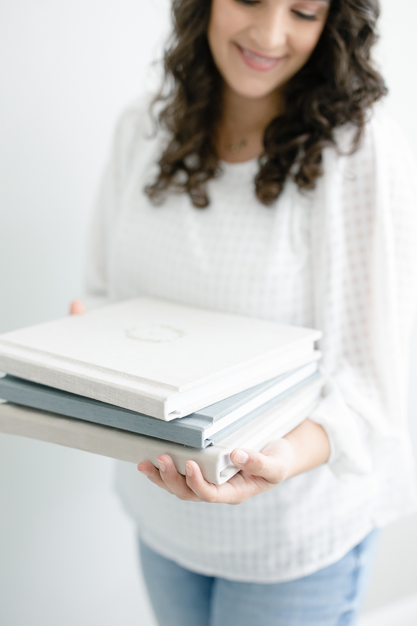 Woman holding custom heirloom albums in pink gray and white | Photo by Little Sunshine Photography