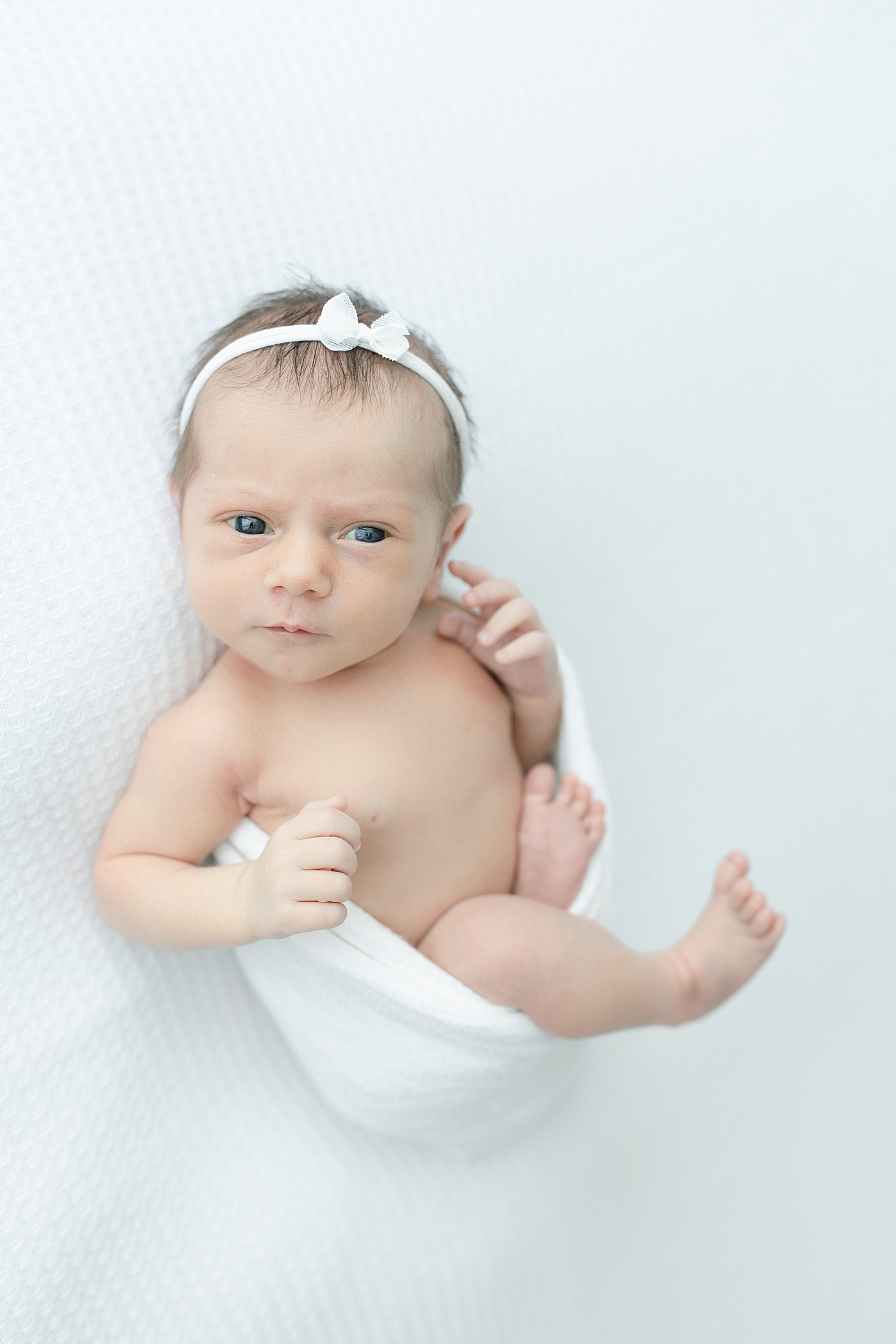 Newborn baby with white headband and bow | Photo by Little Sunshine Photography