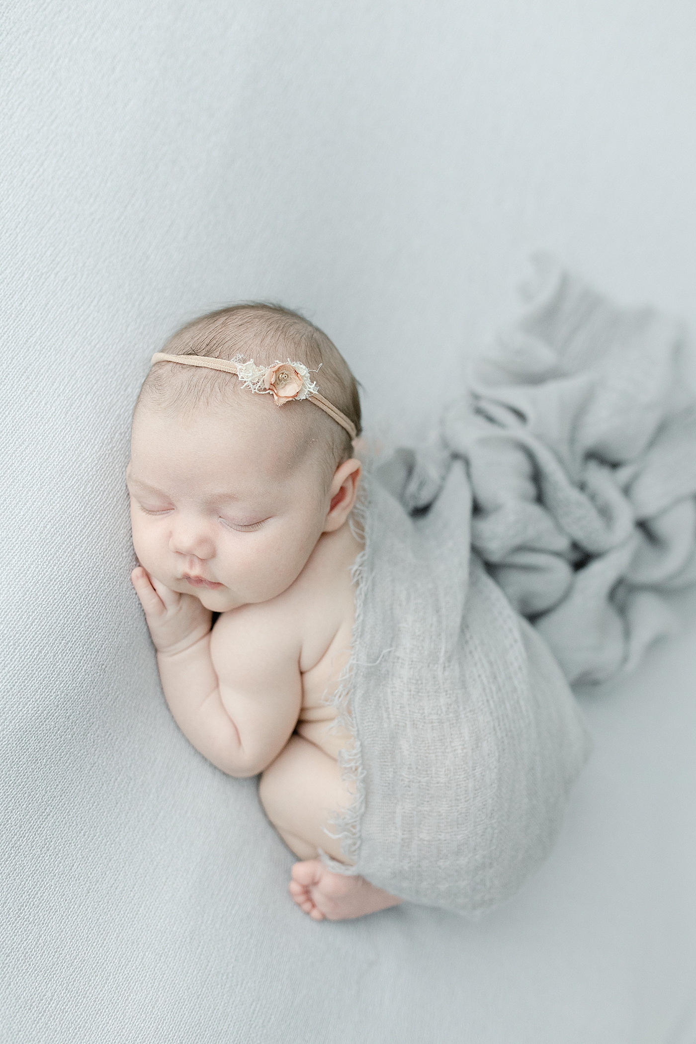 Baby girl asleep on her tummy wrapped in gray swaddle | Photo by Little Sunshine Photography 