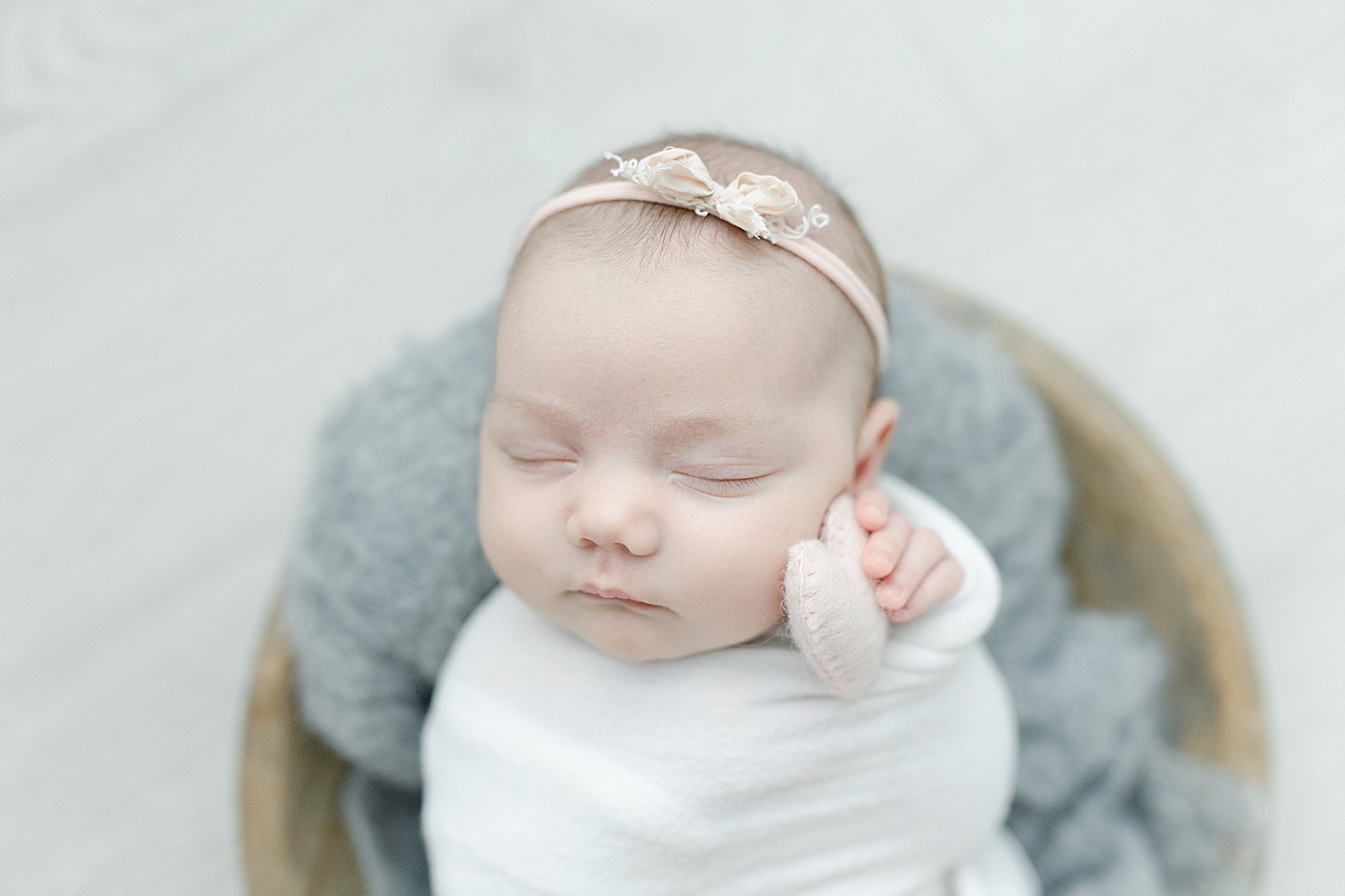 Sleeping baby girl in swaddle holding a tiny pink heart | Photo by Little Sunshine Photography 