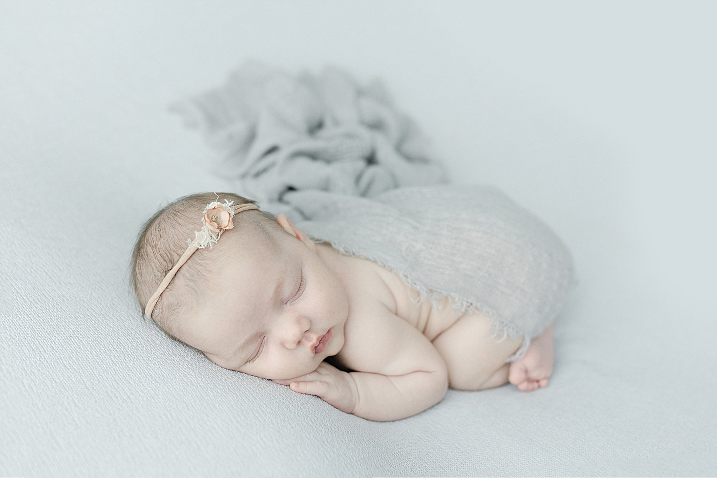 Baby girl wrapped in a gray swaddle sleeping on her tummy | Photo by Little Sunshine Photography 