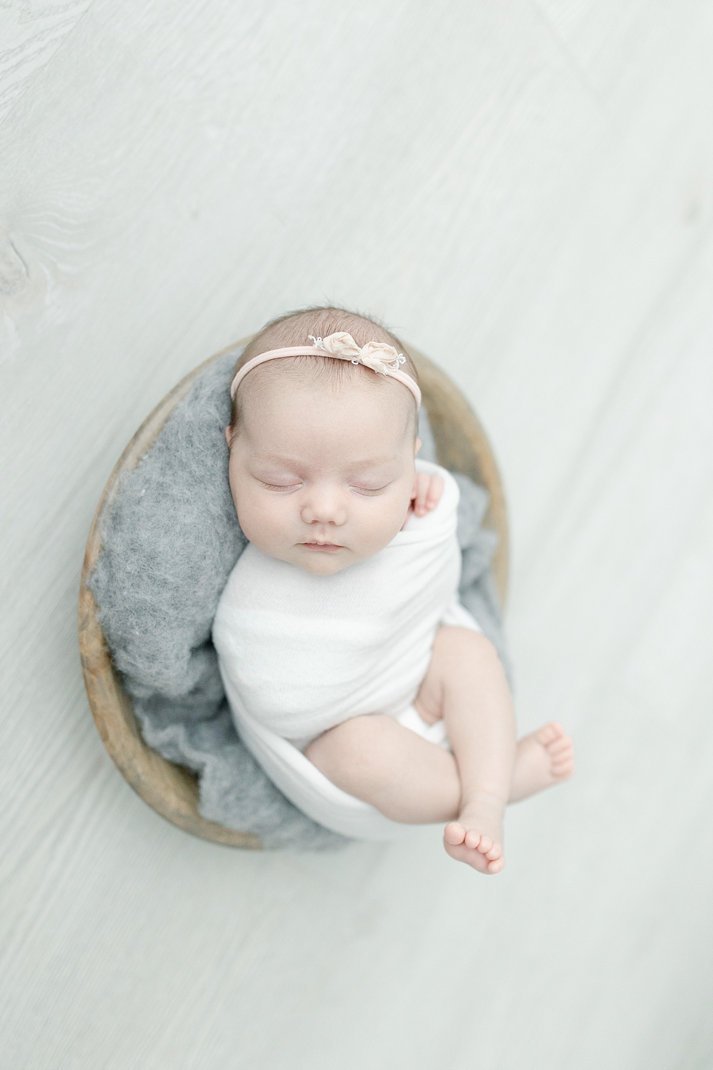 Detail photo of sleeping baby in white swaddle with rose headband | Photo by Little Sunshine Photography 