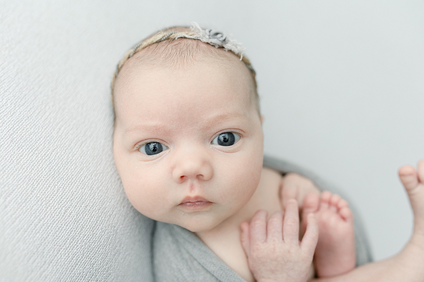 Baby girl in gray looking at the camera | Bay St. Louis newborn photographer Little Sunshine Photography