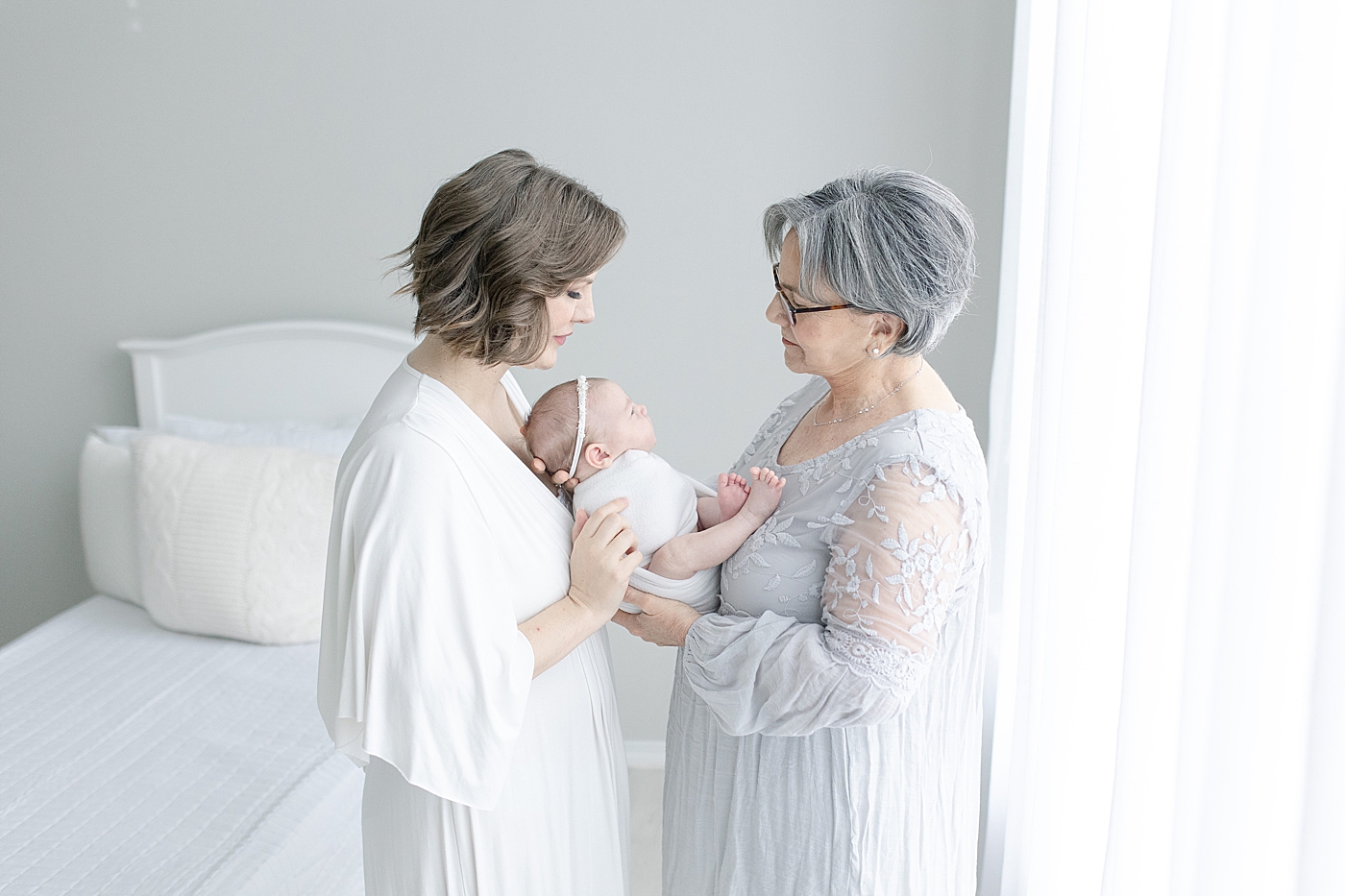 Mom in white and grandma in gray dress hold baby | Photo by Little Sunshine Photography 
