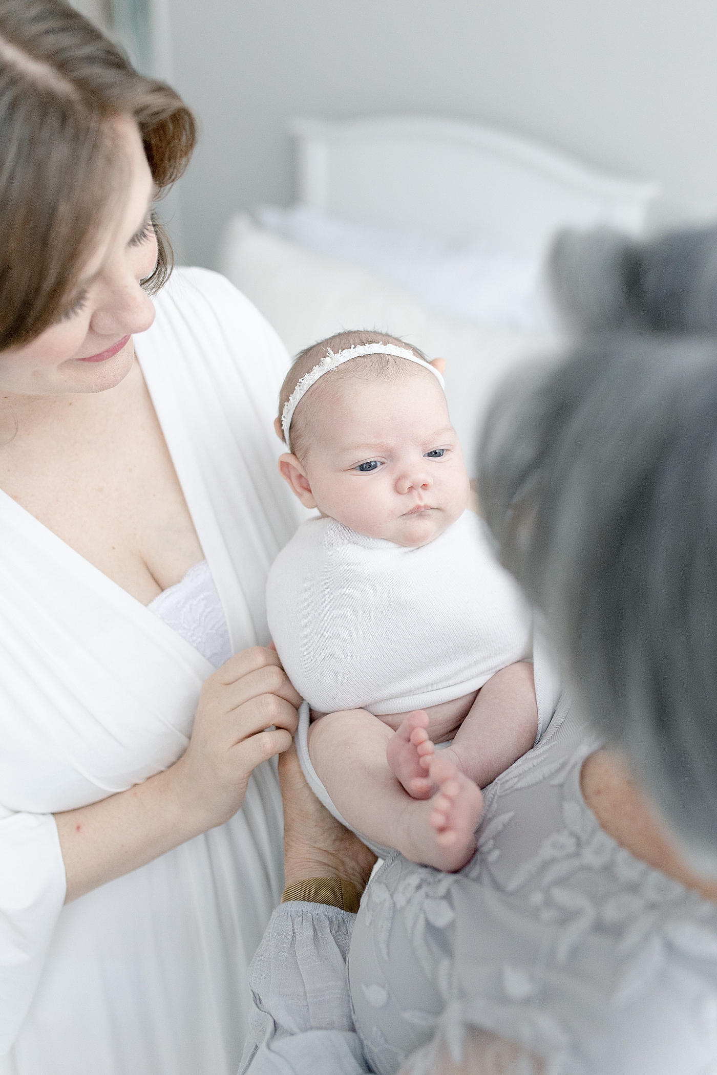Mom and grandma holding baby girl in white headband | Photo by Little Sunshine Photography 