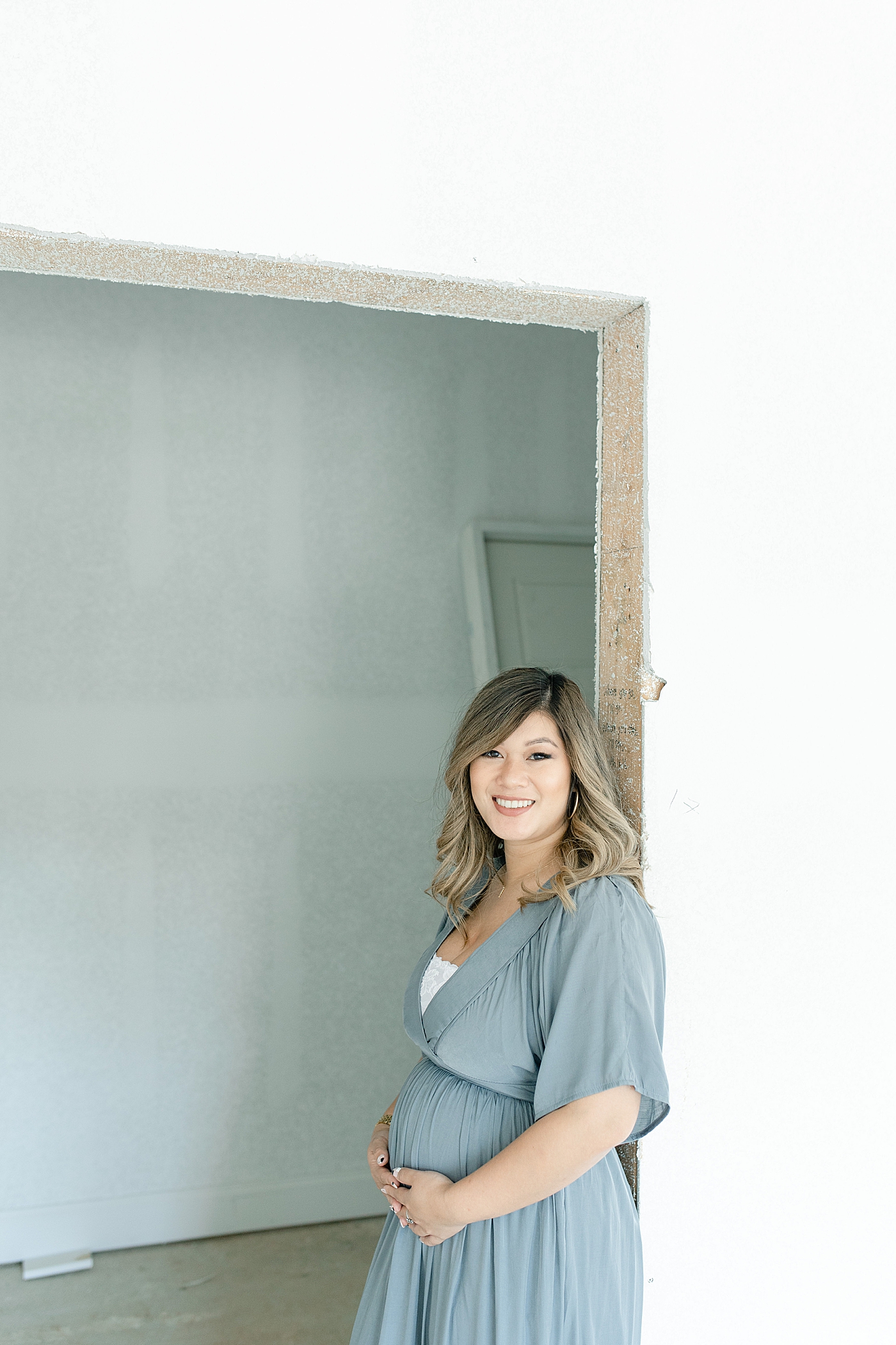 Mom to be in blue in hallway of new home being built | Photo by Little Sunshine Photography 