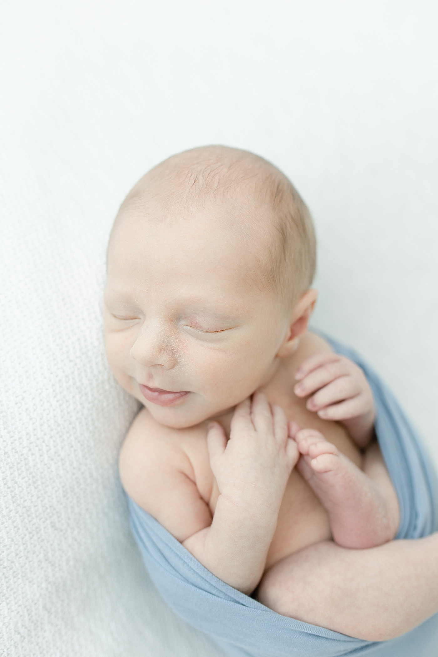 Sleeping newborn baby wrapped in blue swaddle | Photo by Hattiesburg NB photographer Little Sunshine Photography