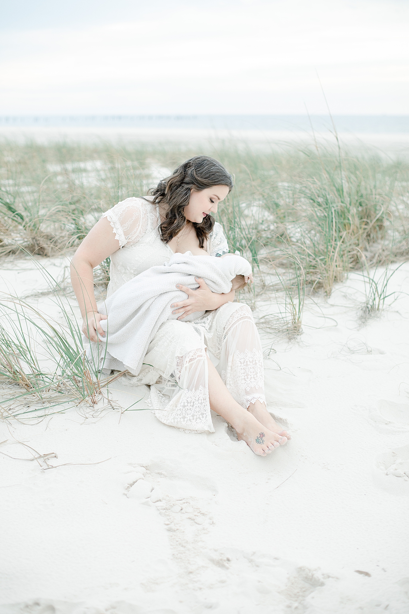 Mom feeding baby girl sitting on the sand at the beach | Photo by Pascagoula Family Photographer Little Sunshine Photography