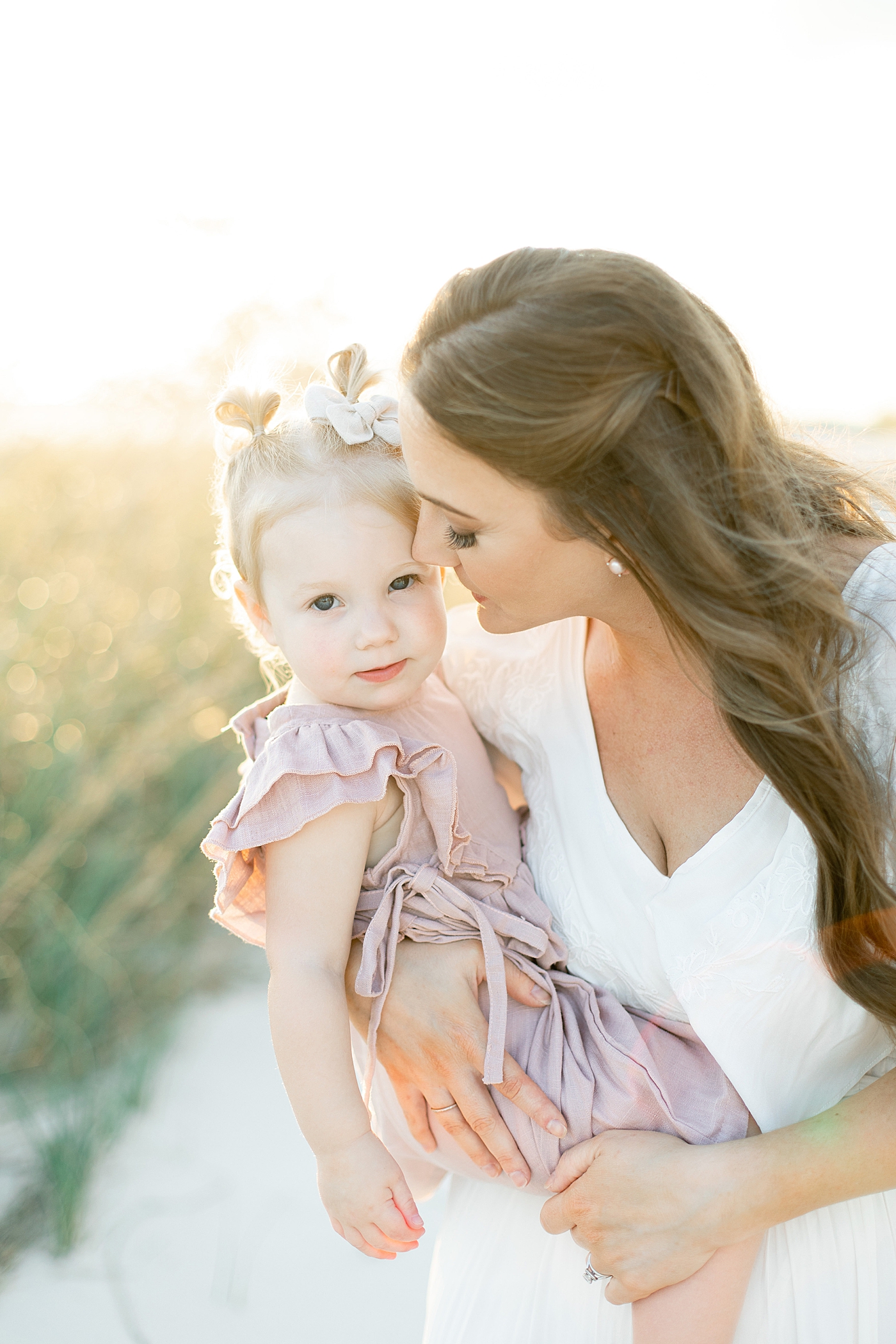 Mom snuggling with toddler daughter on the beach | Photo by Bay St. Louis MS Family Photographer Little Sunshine Photography