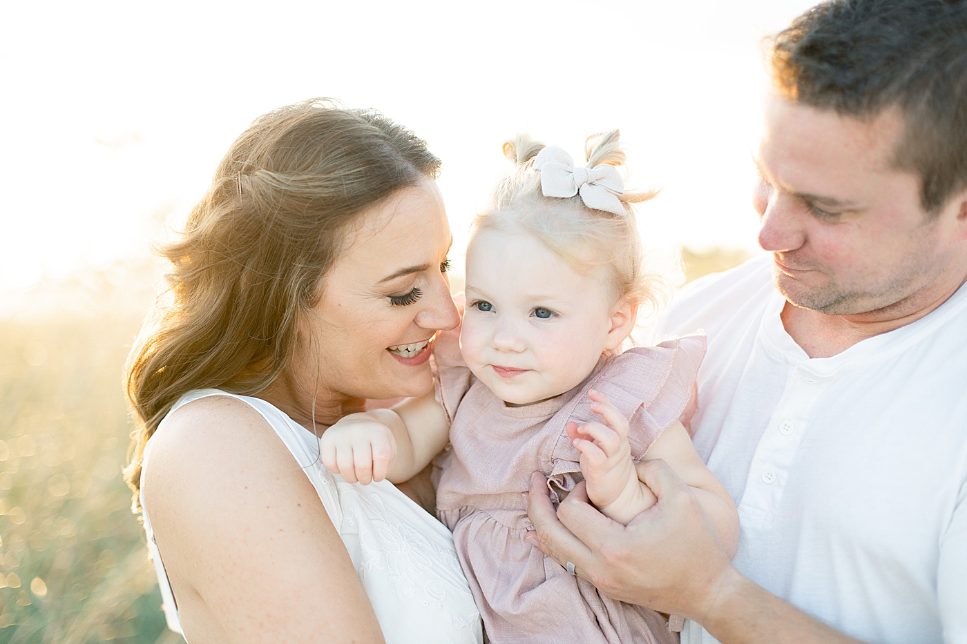 Mom and dad snuggling their toddler girl at the beach | Photo by Bay St. Louis MS Family Photographer Little Sunshine Photography