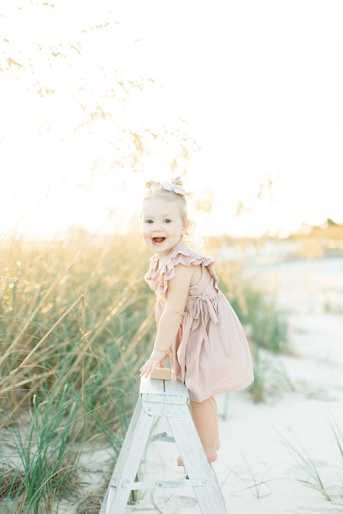 Toddler girl in pink dress and bow smiling | Photo by Bay St. Louis MS Family Photographer Little Sunshine Photography