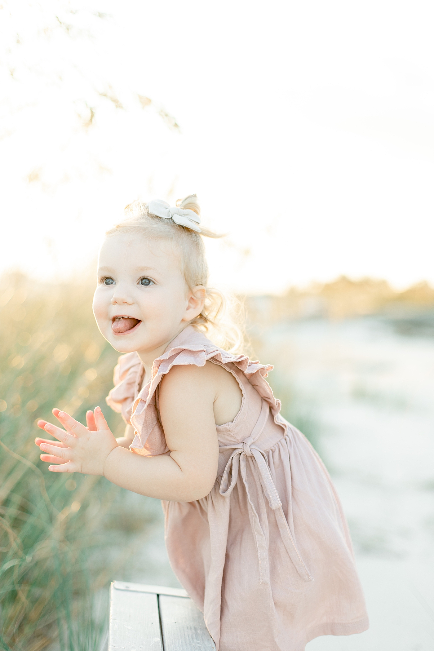 Toddler girl in pink dress clapping her hands | Photo by Little Sunshine Photography