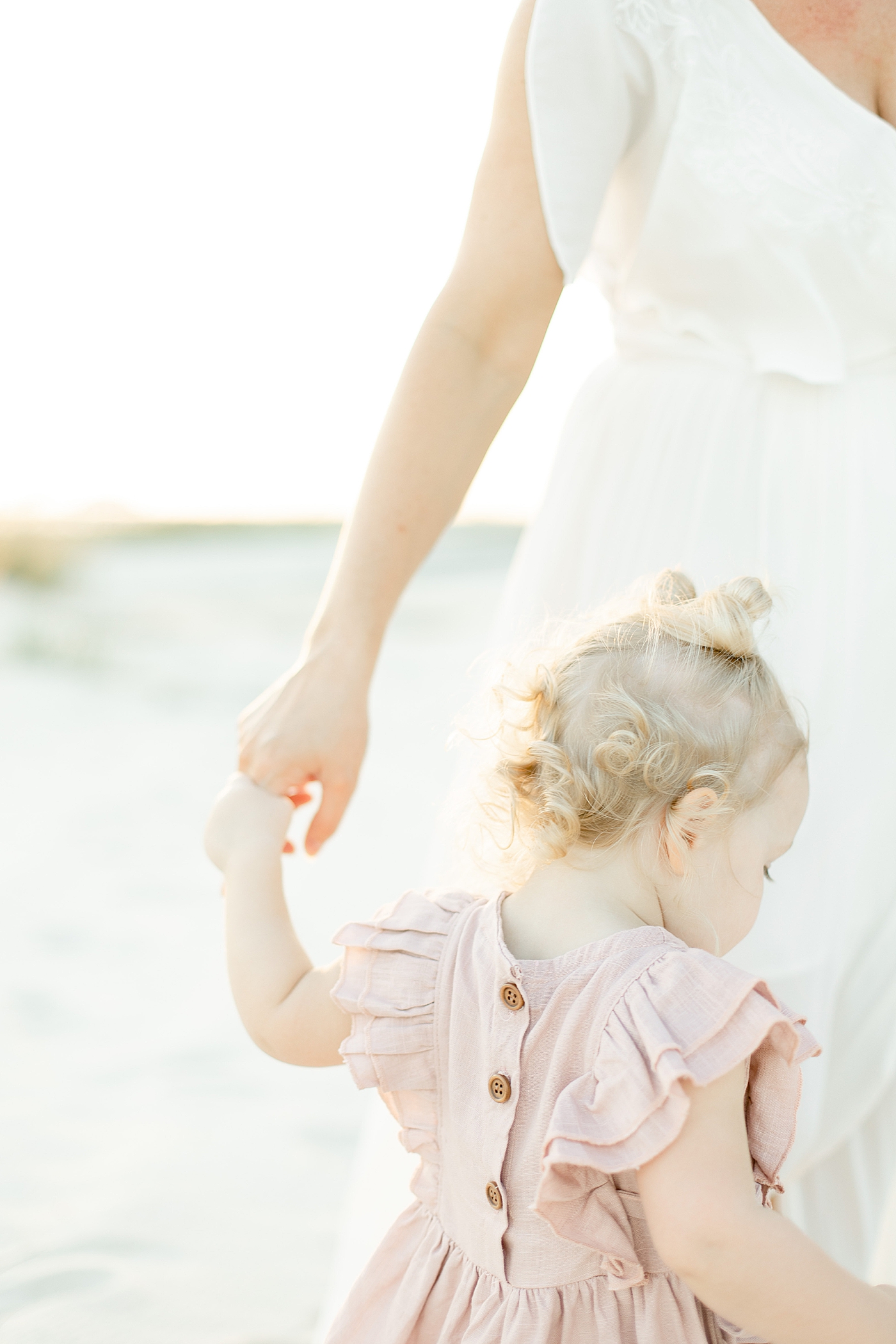 Detail of toddler in pink button dress holding moms hand | Photo by Bay St. Louis MS Family Photographer Little Sunshine Photography