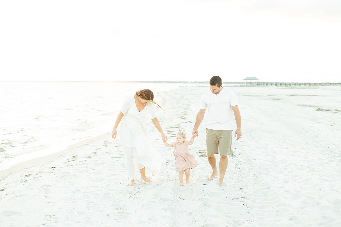 Mom dad and baby girl walking on the beach at sunset | Photo by Little Sunshine Photography