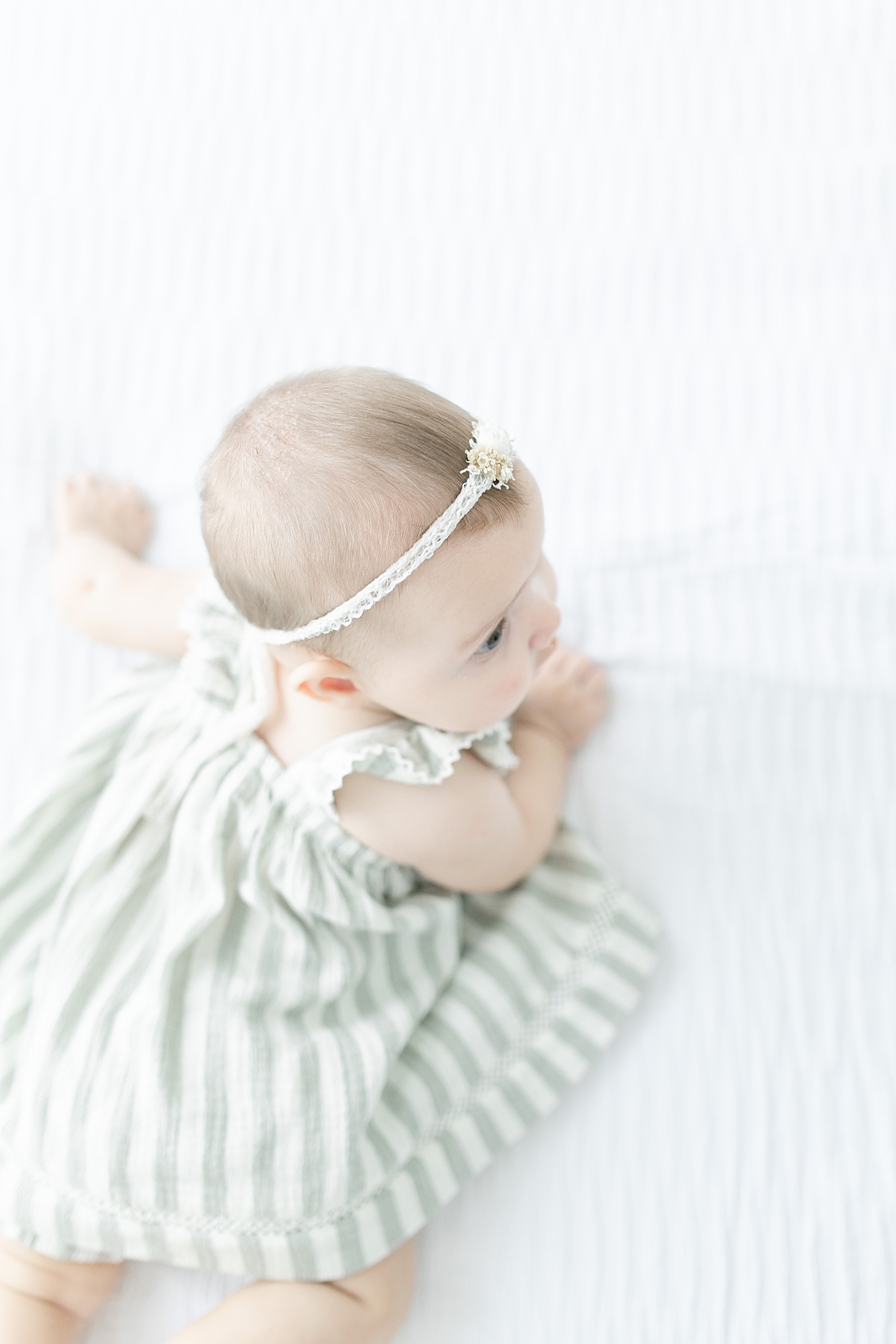 Details from above of baby girl in striped dress with headband | Photo by Little Sunshine Photography