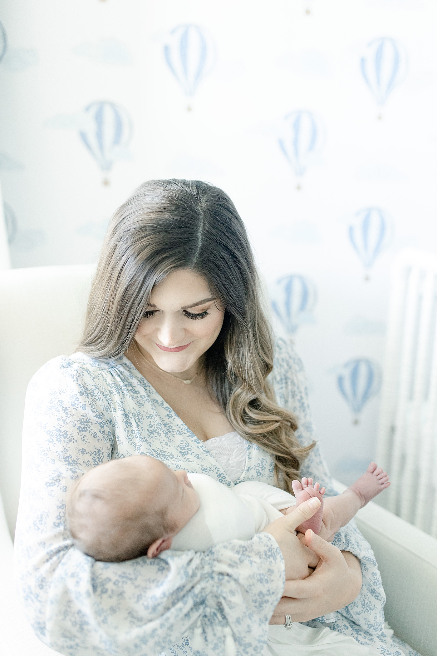Mom smiling down on newborn baby boy she's holding | Photo by Little Sunshine Photography