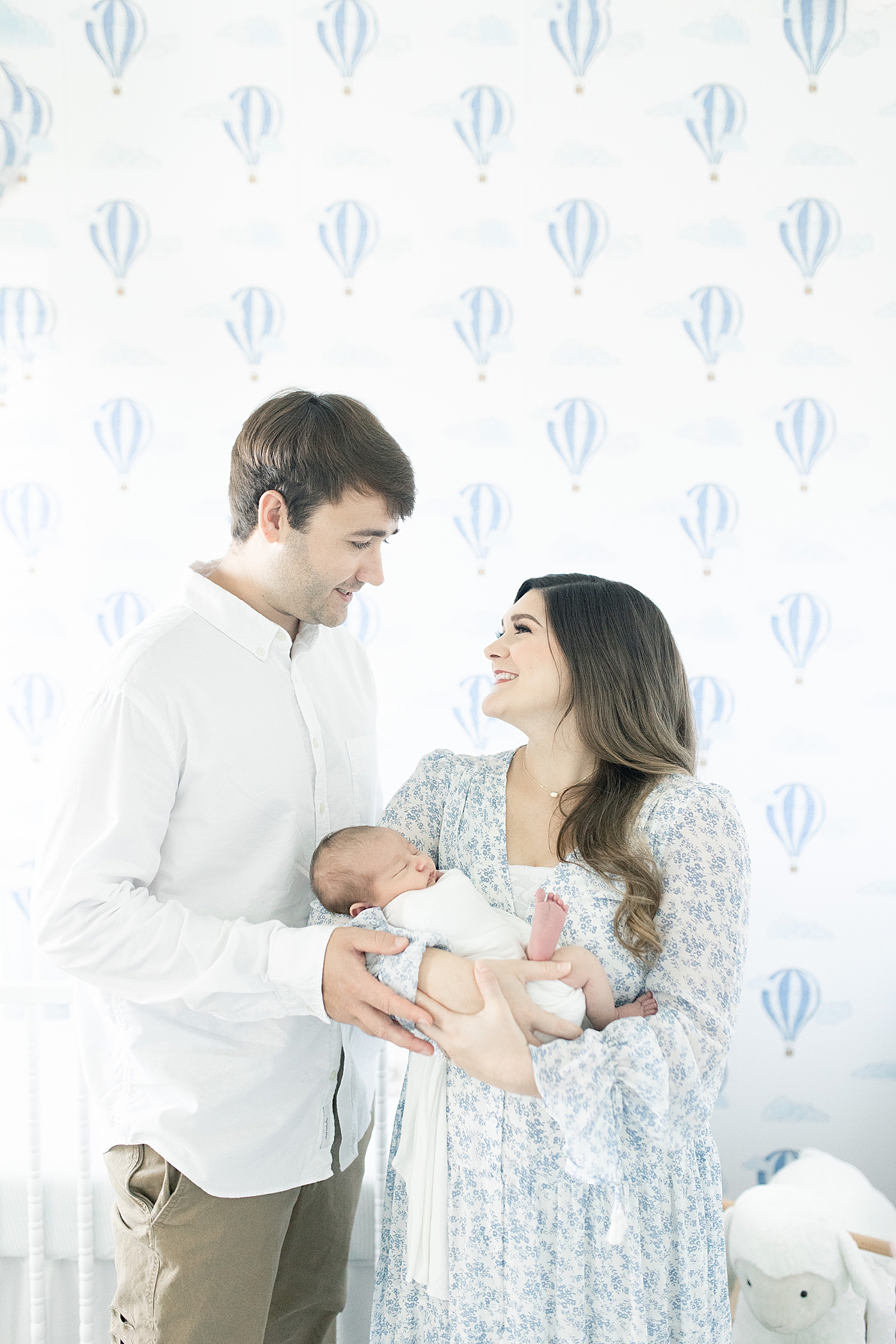 Mom and dad smiling while holding their baby | Photo by Long Beach Newborn Photographer Little Sunshine Photography