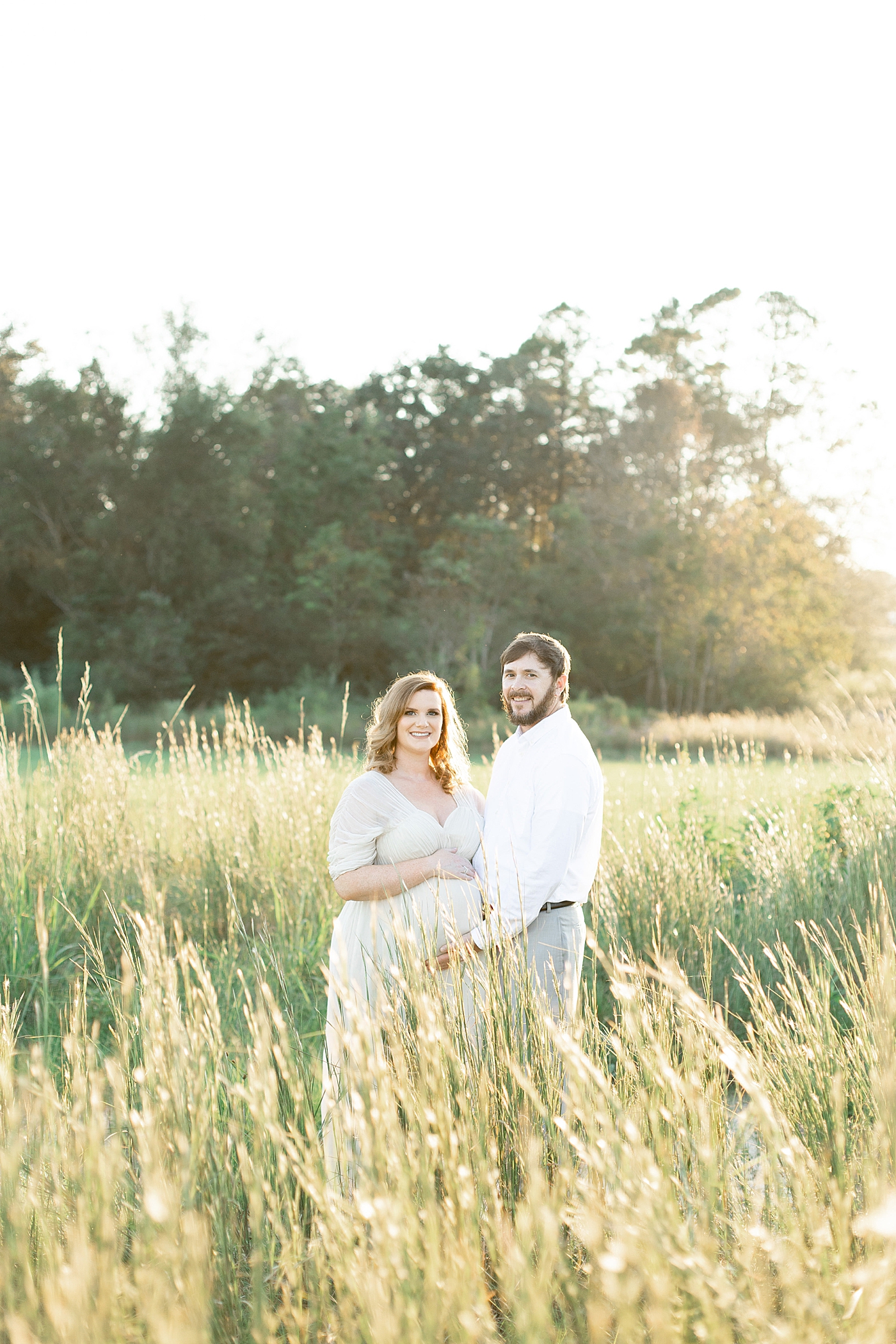 Mother and father to be in a field | Photo by Little Sunshine Photography 