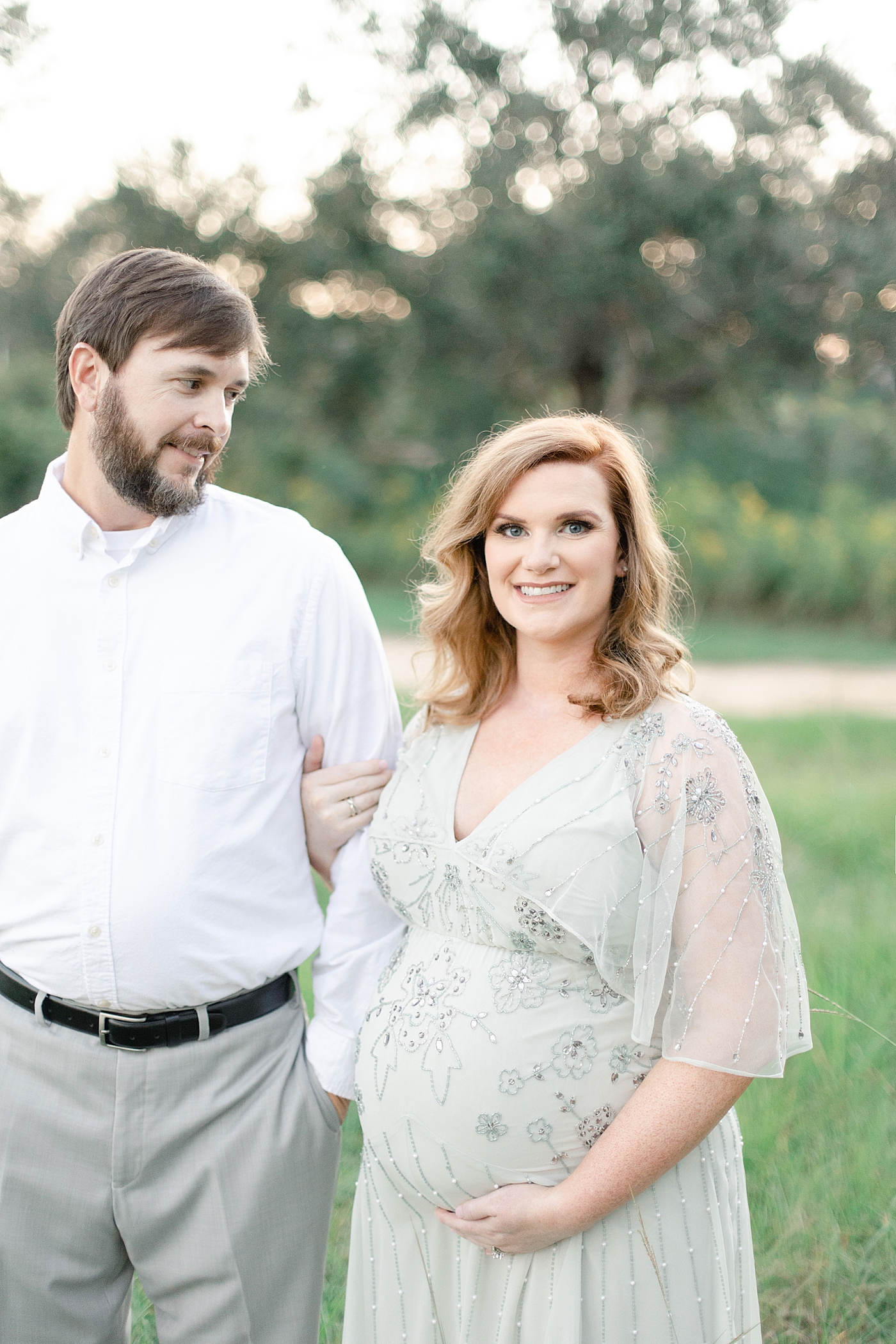 Mother to be looking at the camera father to be looking at her | Photo by Little Sunshine Photography 