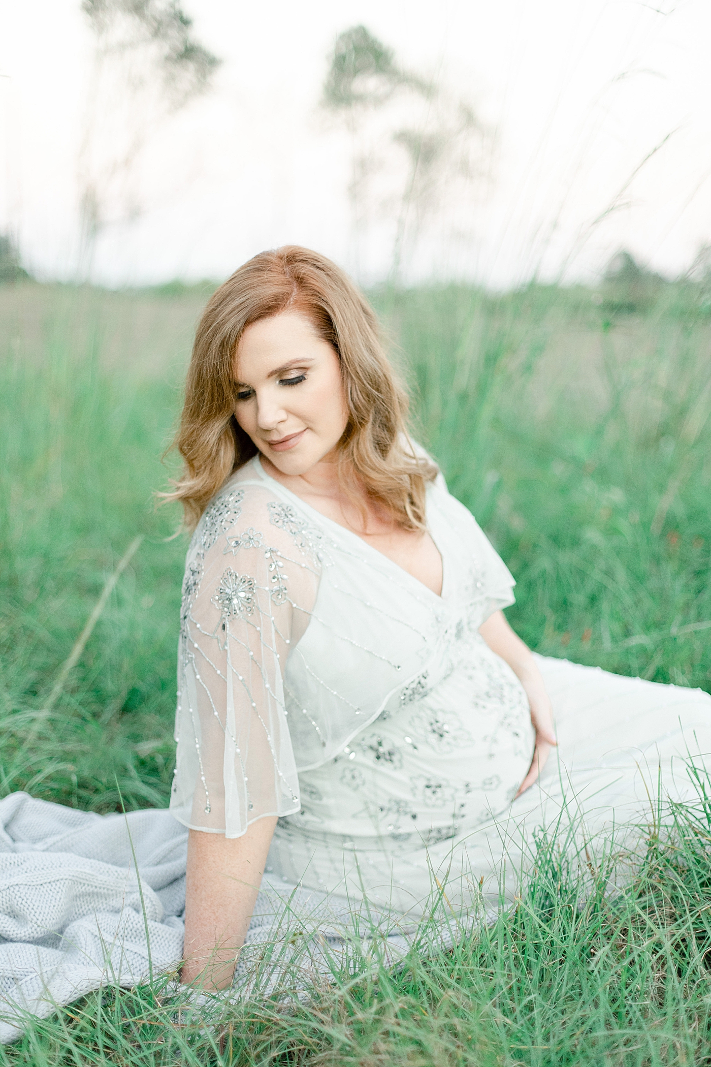 Mother to be sitting in the grass | Photo by Little Sunshine Photography 