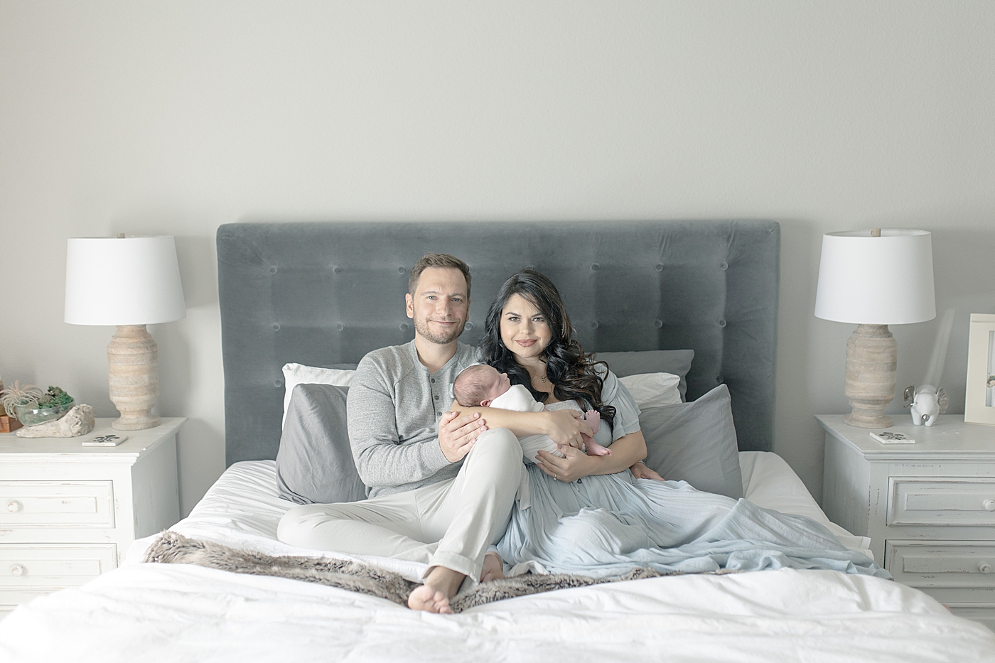 Dad and mom with newborn baby on their bed | Photo by Little Sunshine Photography