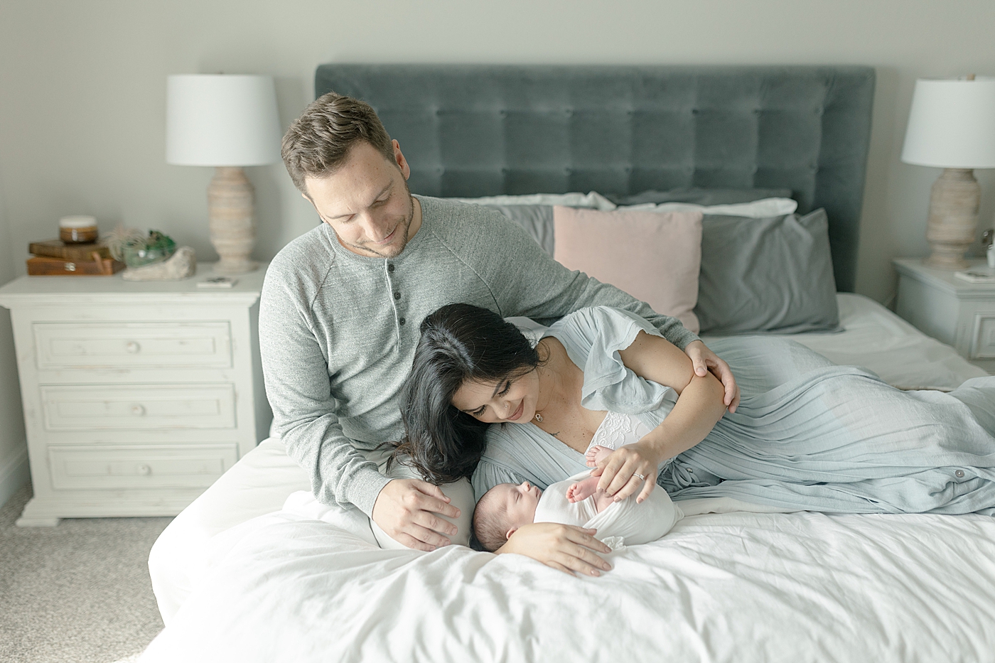 Mom and dad snuggling baby boy on their bed | Photo by Little Sunshine Photography